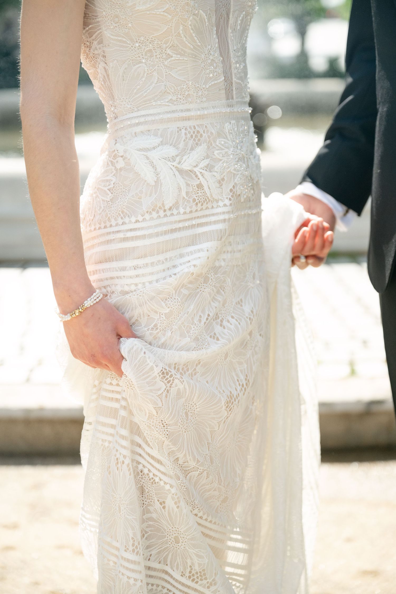 Close-up detail of a white lace wedding dress showing intricate embroidery and pattern work.