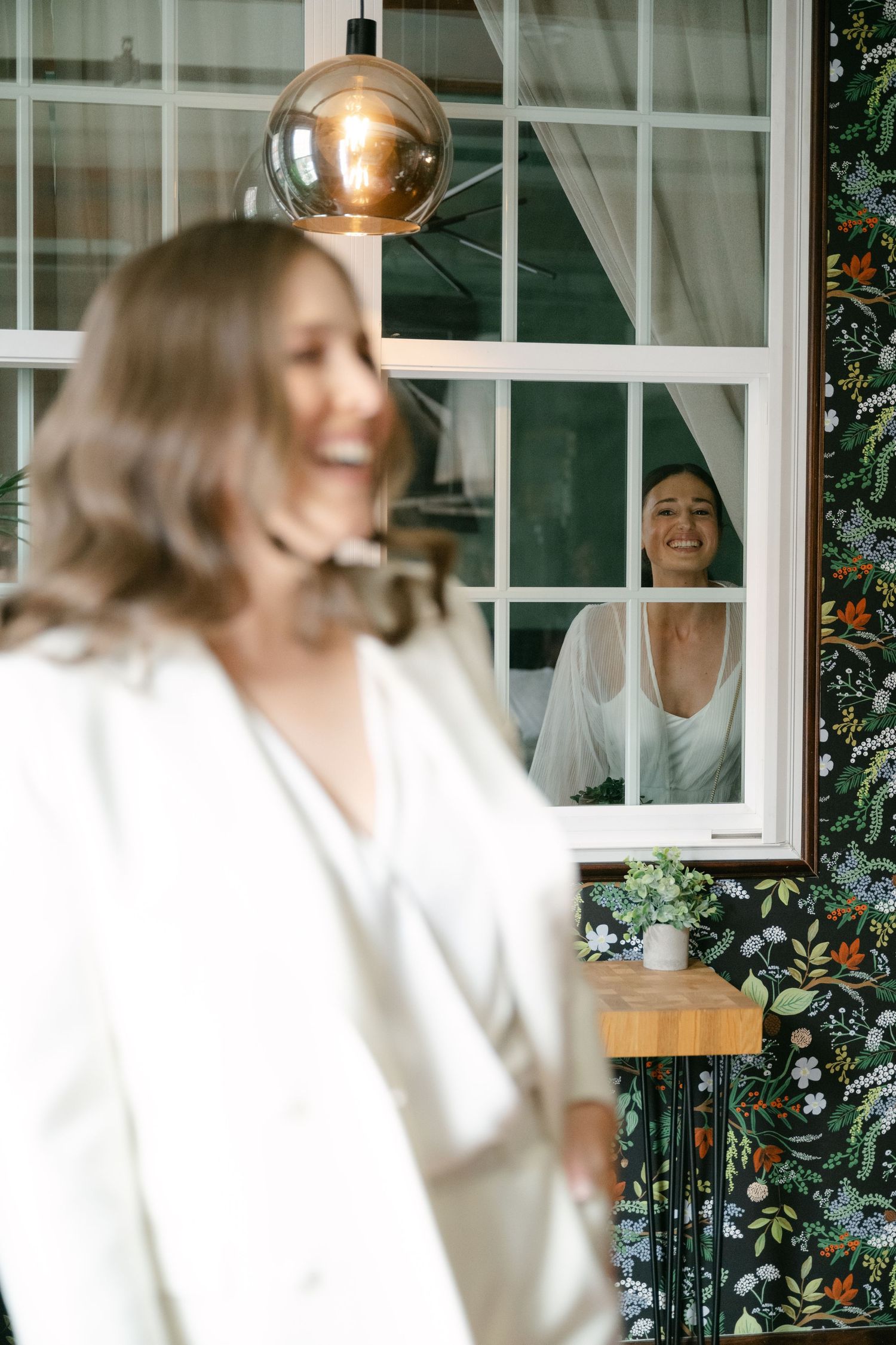 A candid moment captured through a window with a modern glass pendant light fixture.