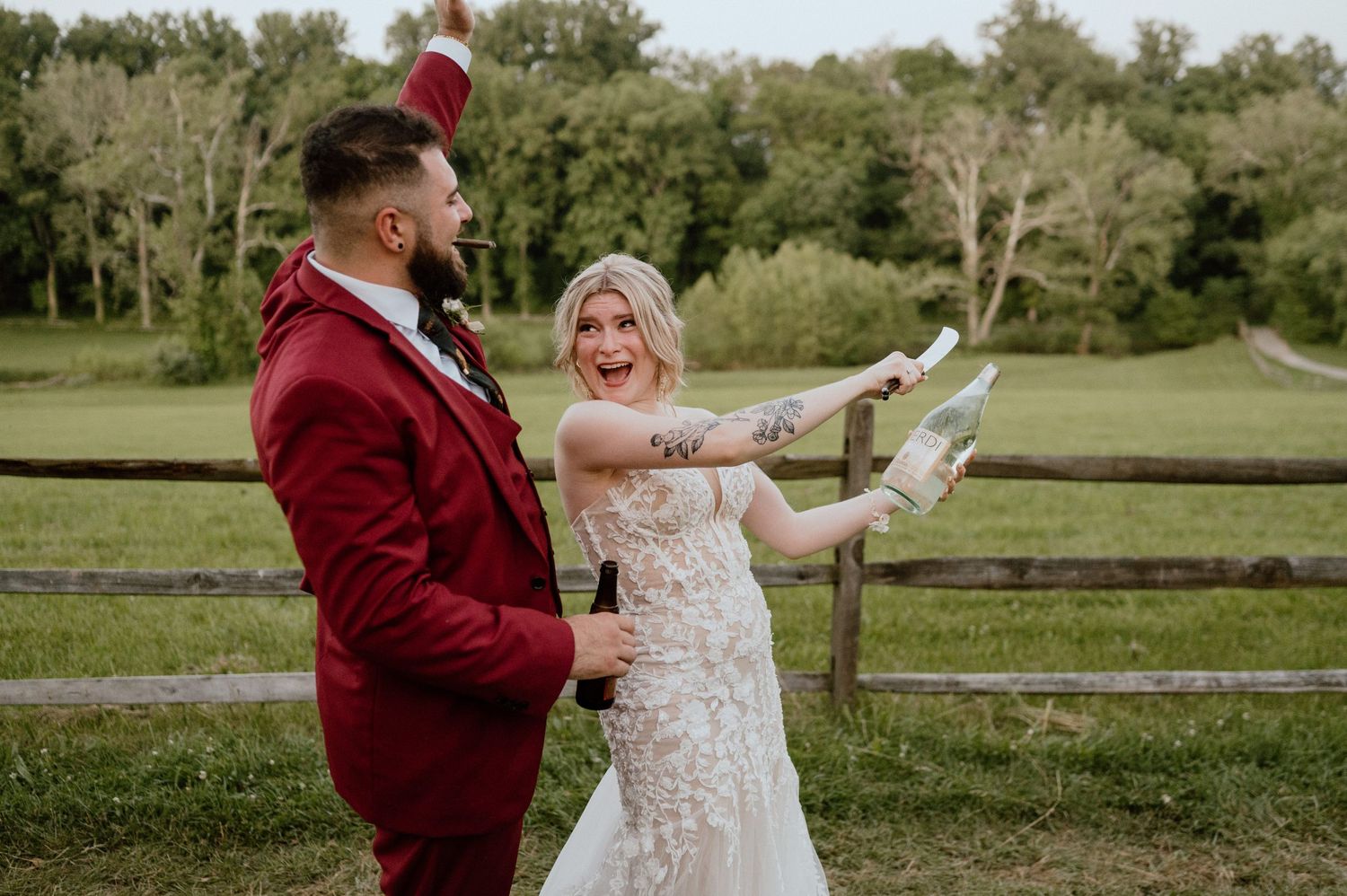 A couple in wedding attire having fun and posing playfully by a rustic fence.
