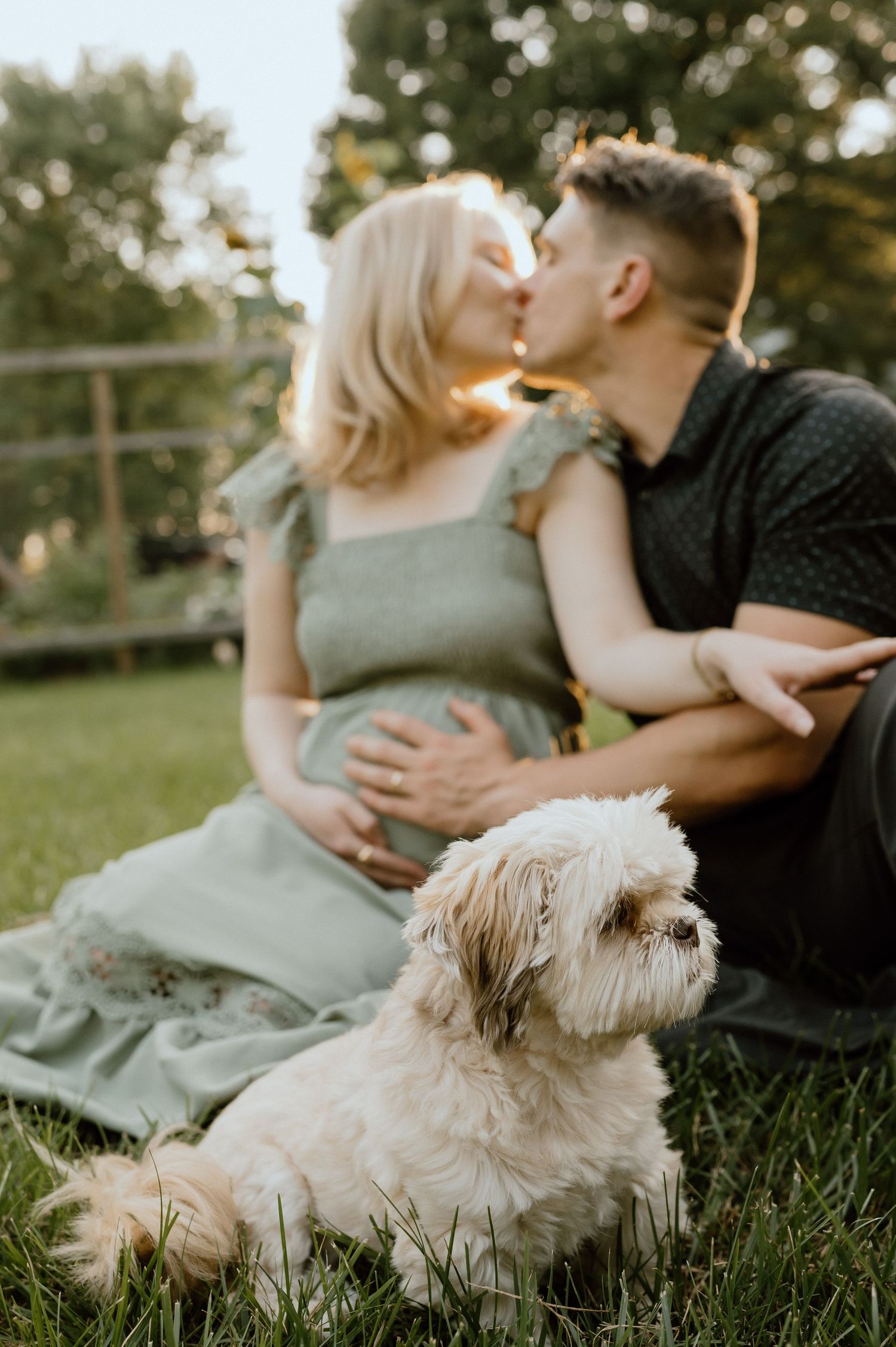 Intimate moment shared on grass with small white dog sitting nearby.