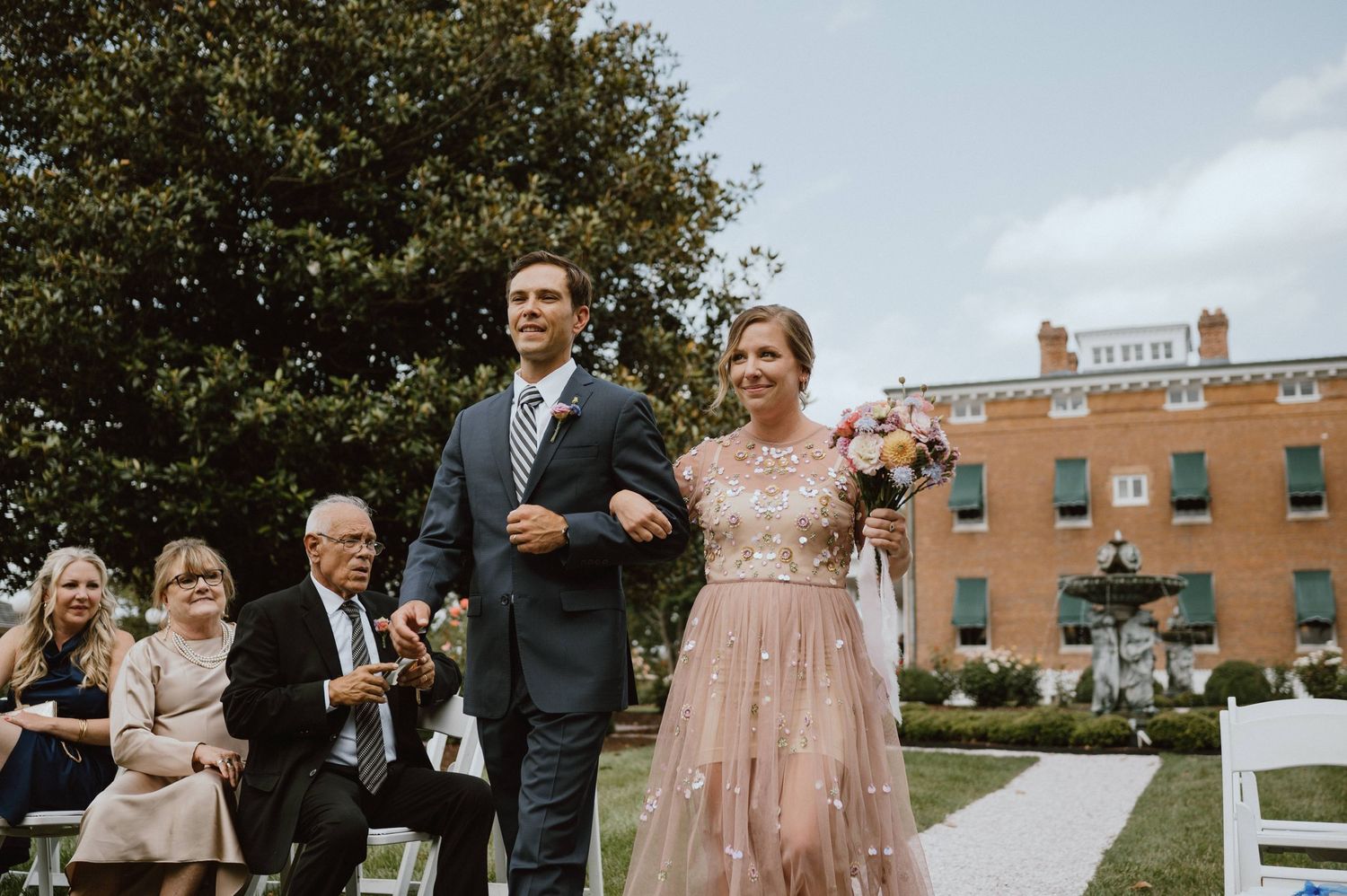 Wedding ceremony recessional on the lawn of a historic brick mansion.