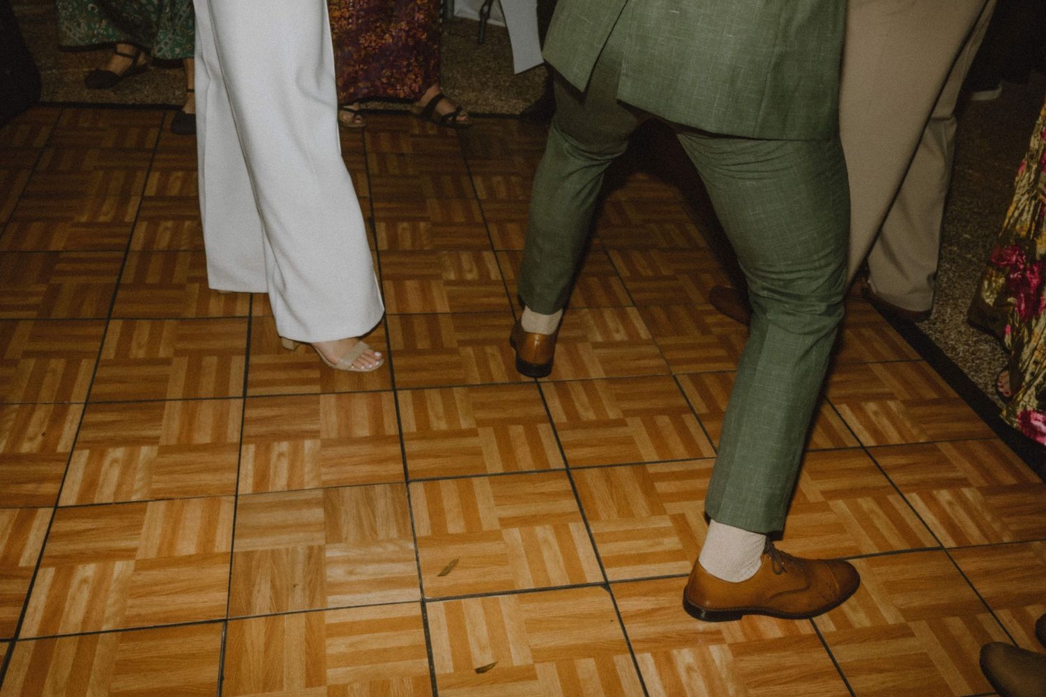 Close-up of dancers' feet on a parquet dance floor showing formal party attire.