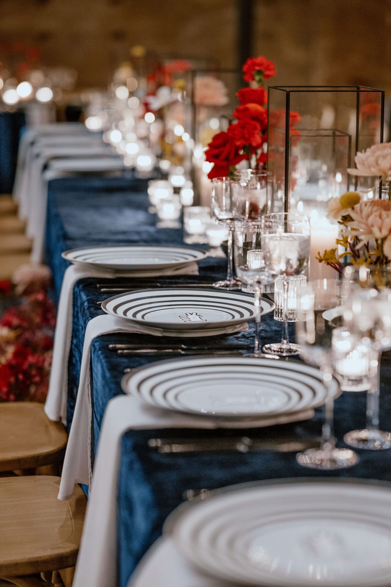 Elegant table setting with navy linens, striped plates, and candle centerpieces.