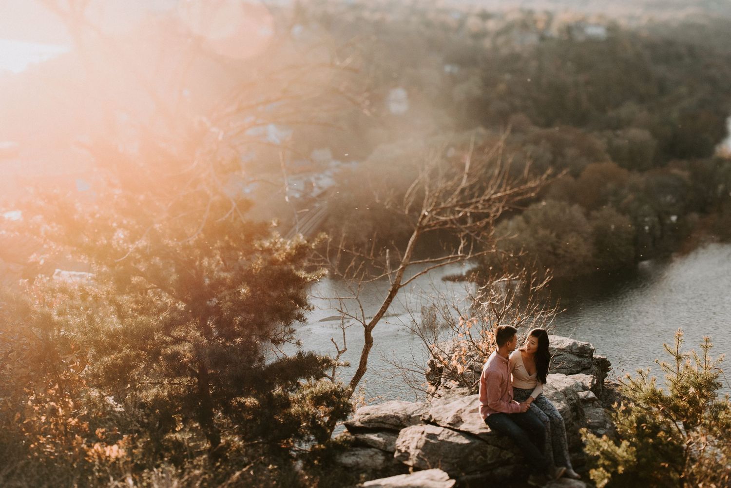 Sunset engagement photo session on rocky overlook above winding river.