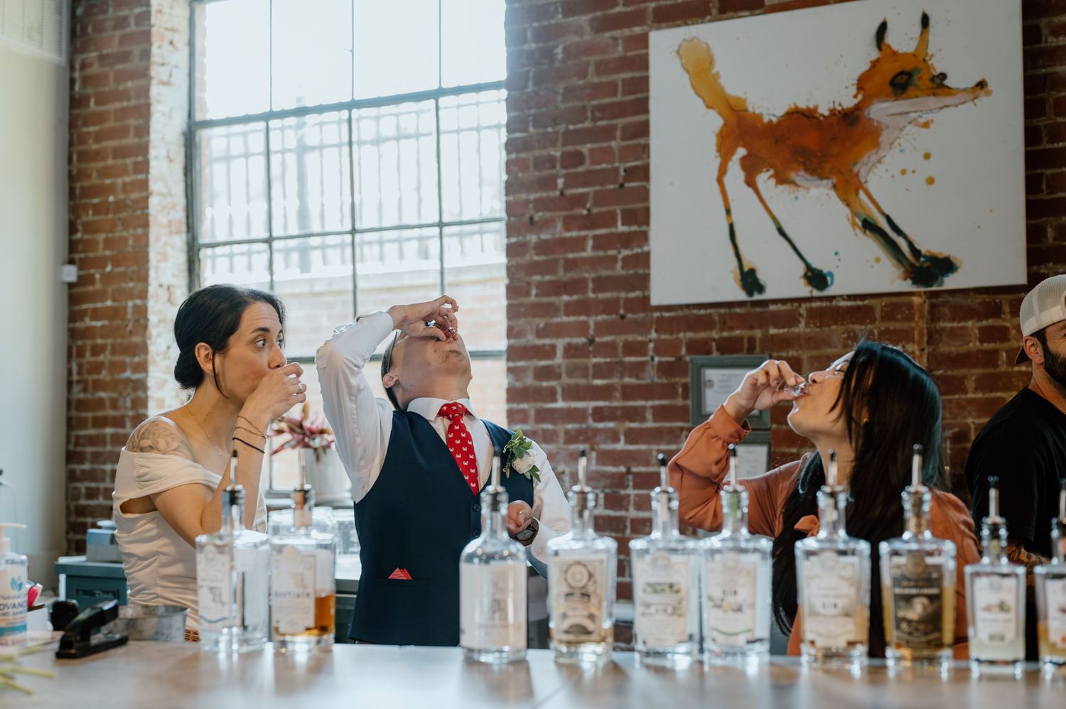 Group enjoying drinks at a bar with exposed brick walls and fox artwork.