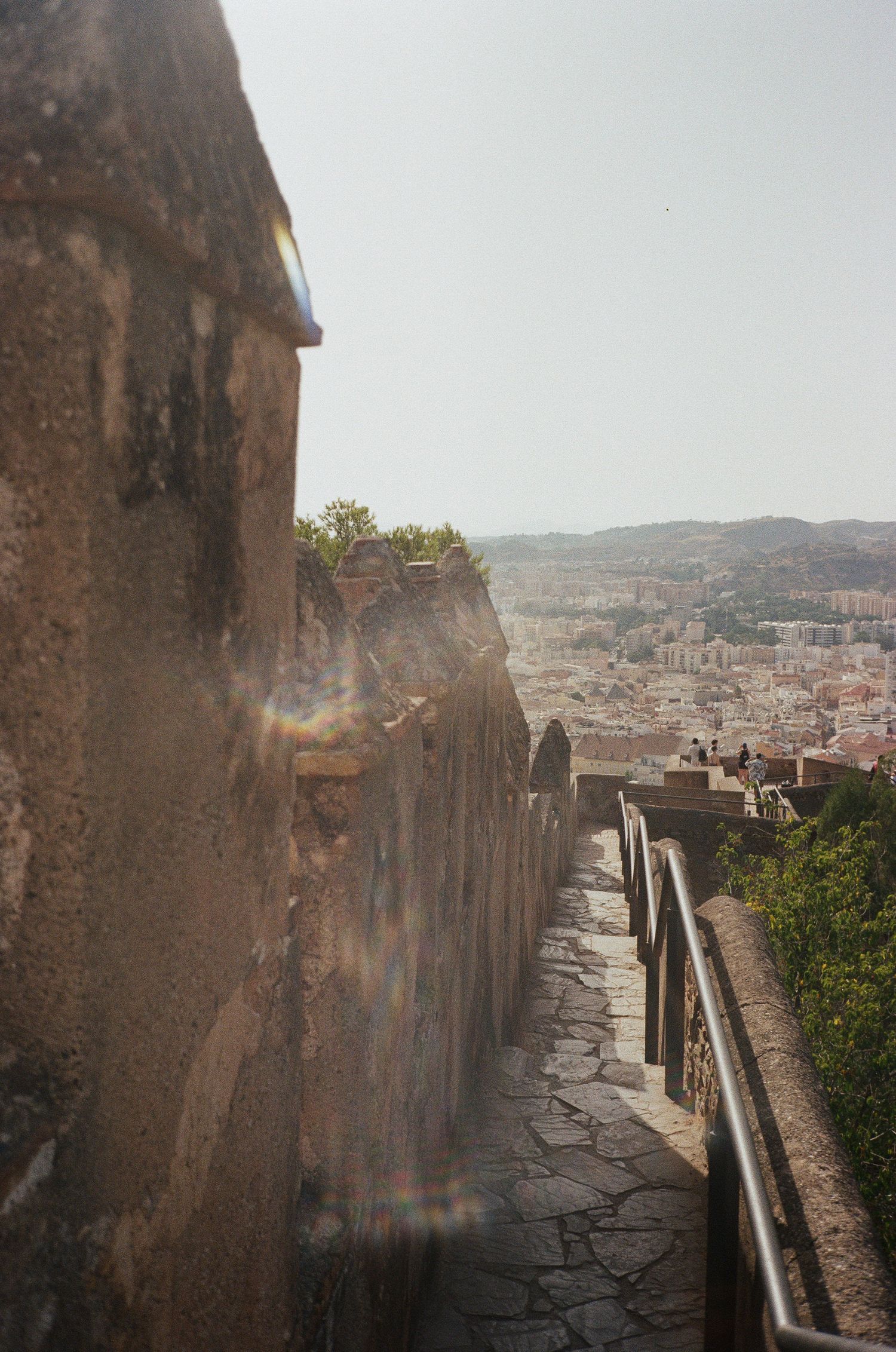 Ancient stone walkway with weathered walls overlooking a cityscape.