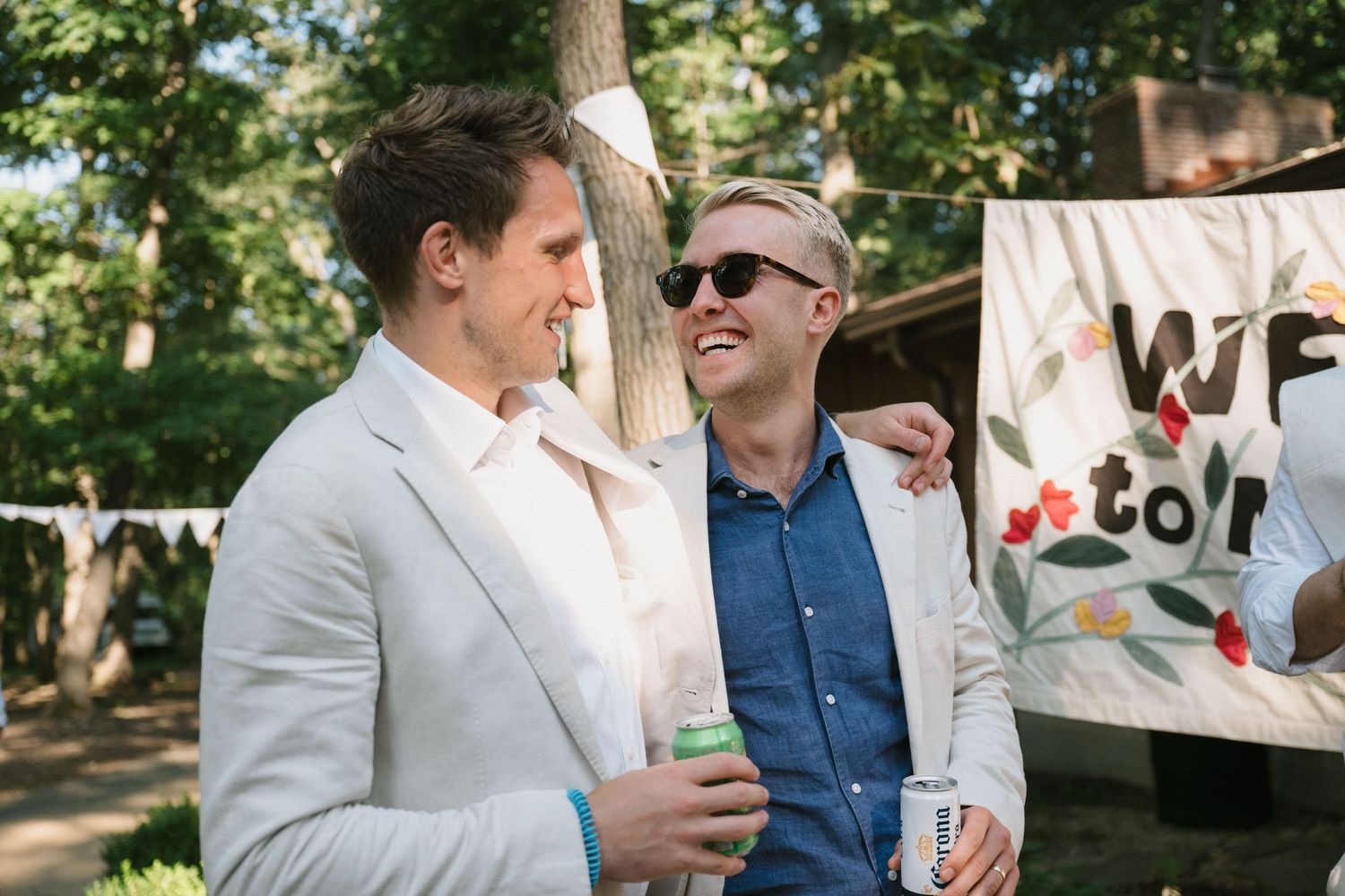 Two guests chat during an outdoor celebration with banners visible in background.