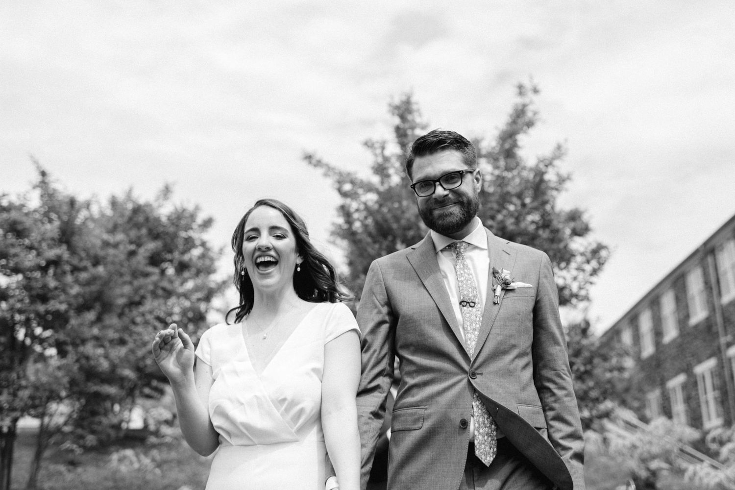 A joyful black and white wedding portrait taken in a garden setting.