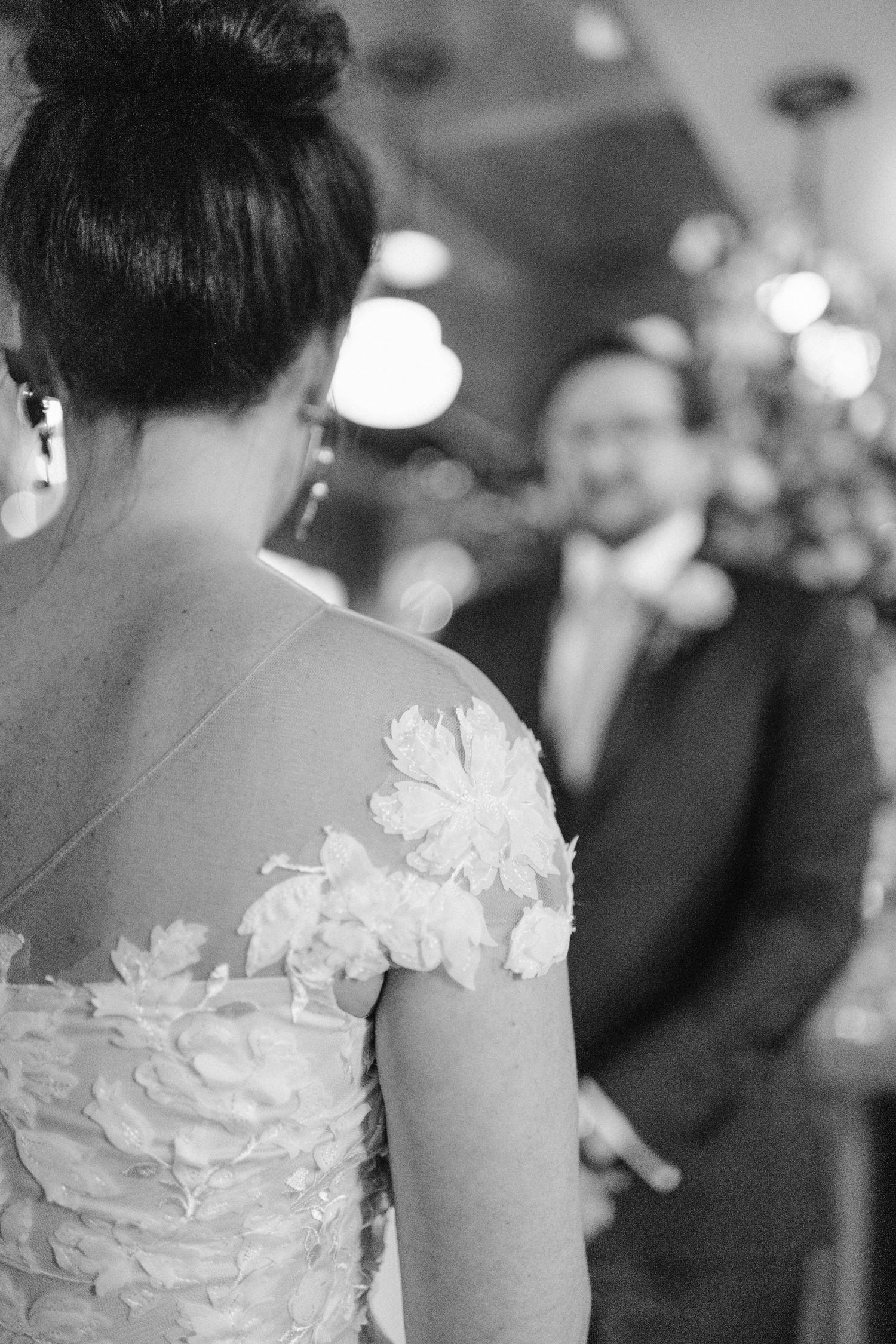 Close-up view of a detailed floral lace wedding dress with soft lighting.