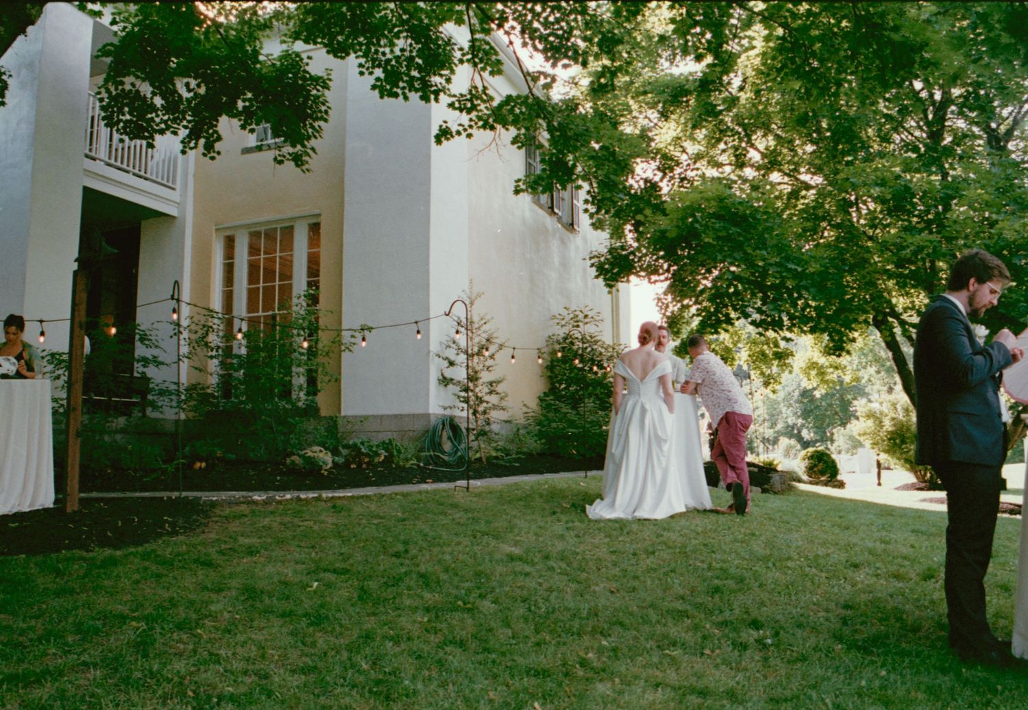 Outdoor wedding ceremony under string lights and tree branches.