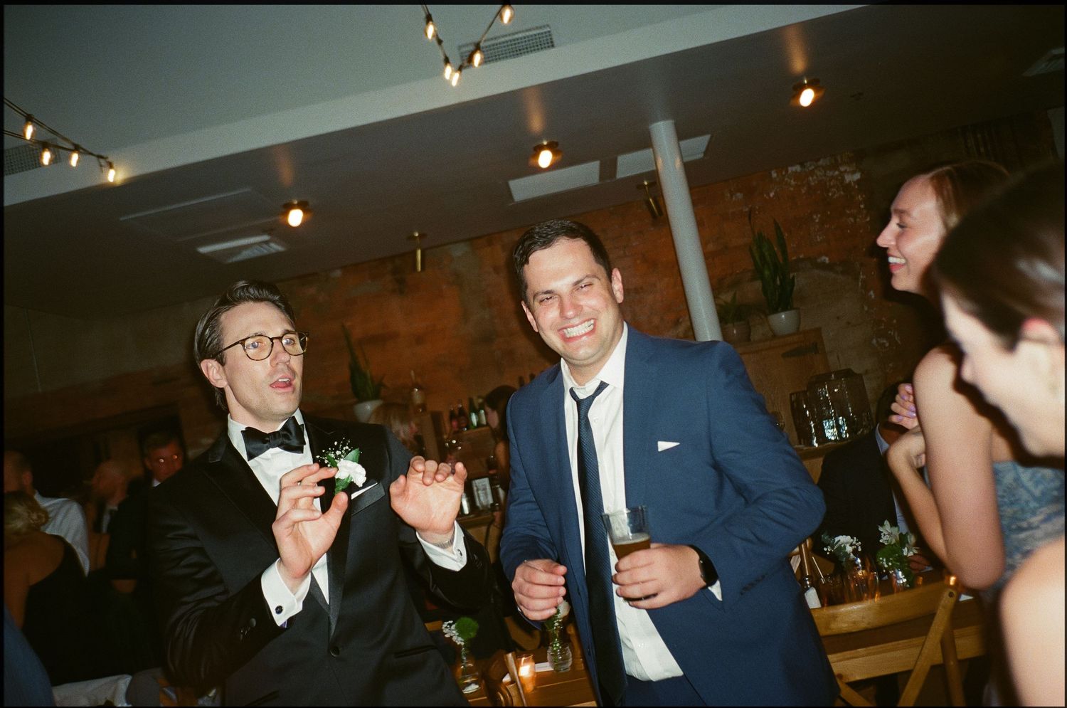 A social gathering at an indoor venue with people enjoying drinks under ambient lighting.