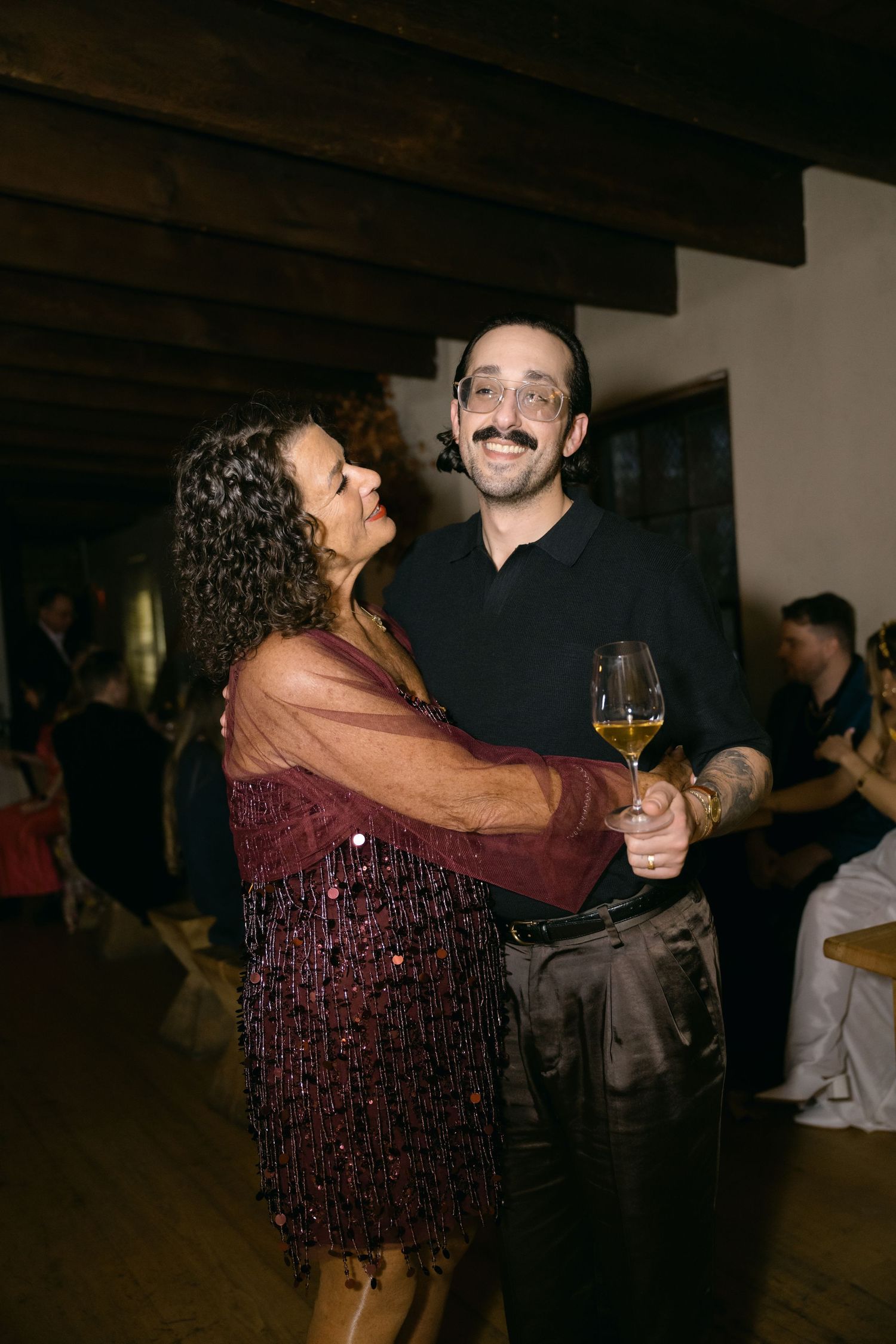 Two people smiling and dancing together at a party with wine glasses in hand at Fadensonnen in Baltimore