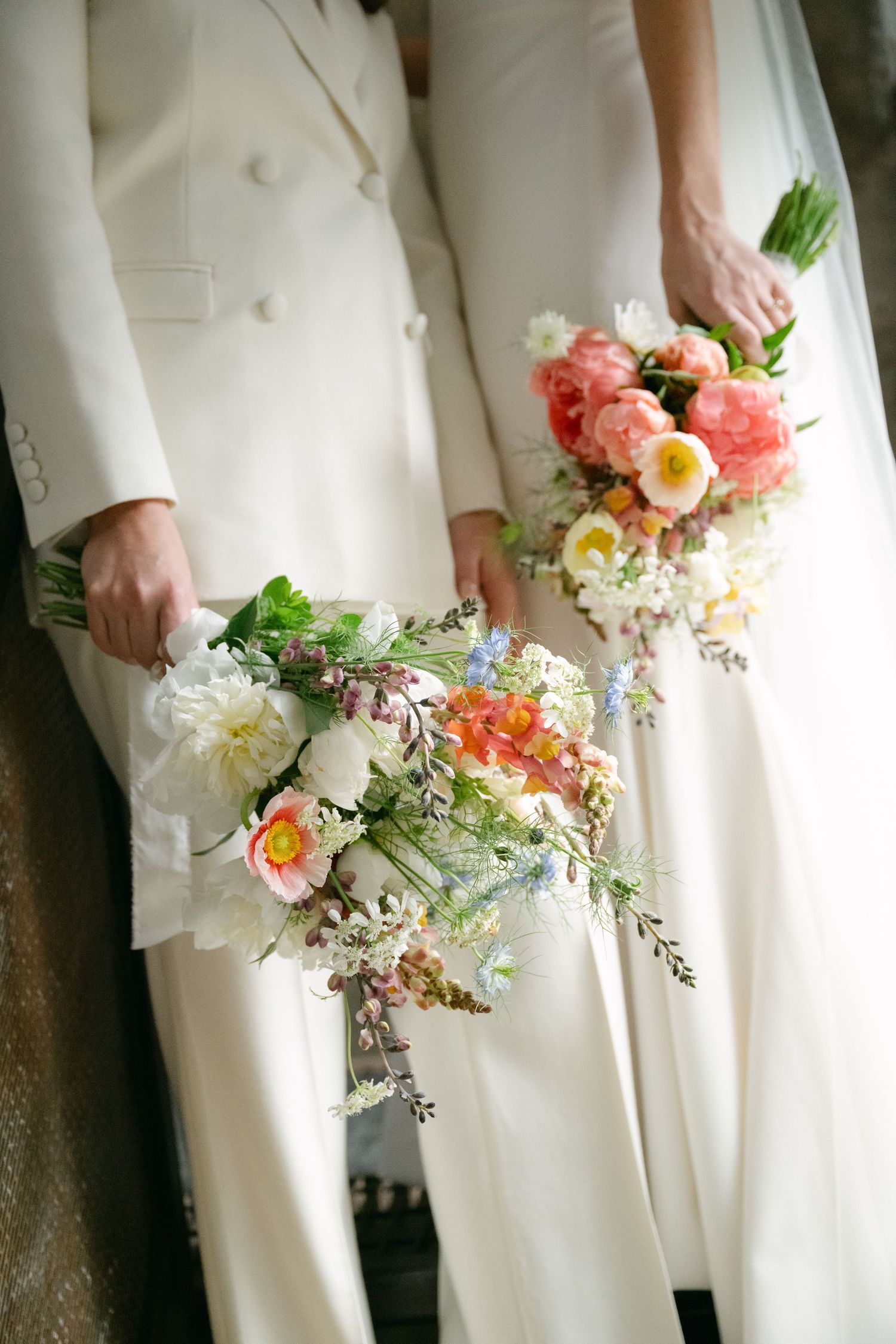 Two wedding bouquets with coral and white flowers against crisp white formal attire.