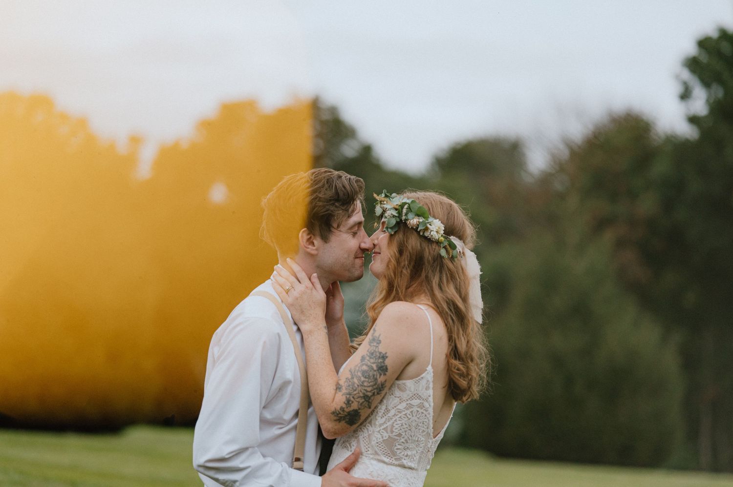 Romantic outdoor wedding portrait with autumn colors and floral crown at sunset.
