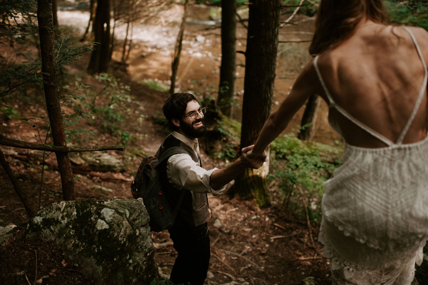 Two people share a moment on a forest trail during an intimate outdoor ceremony.