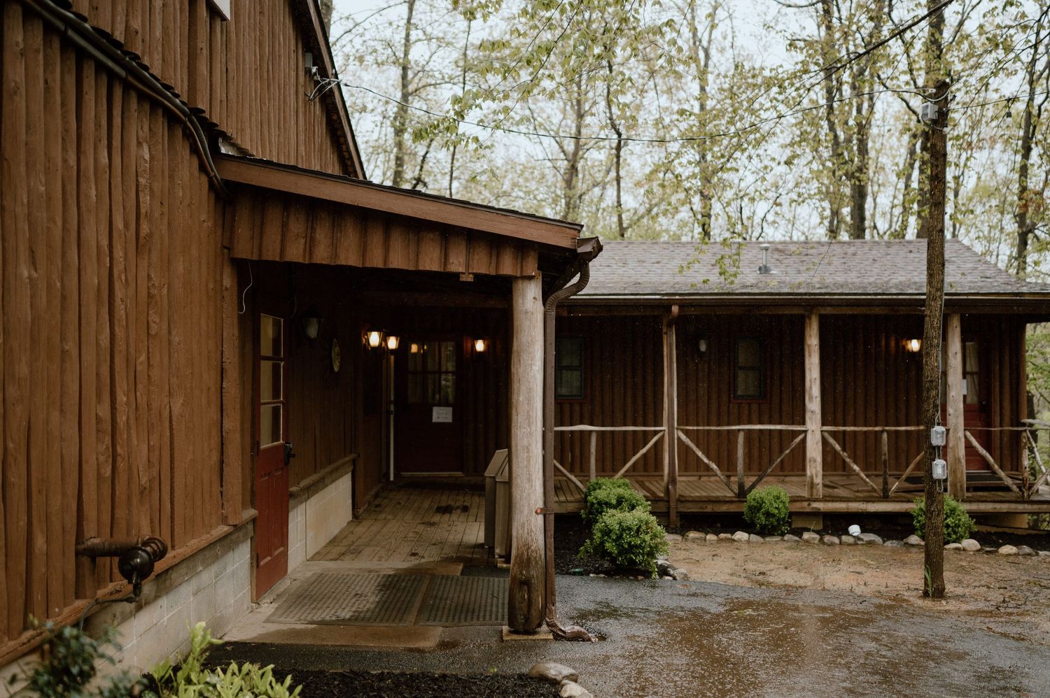Exterior view of a rustic brown wooden lodge with string lights and covered porch.