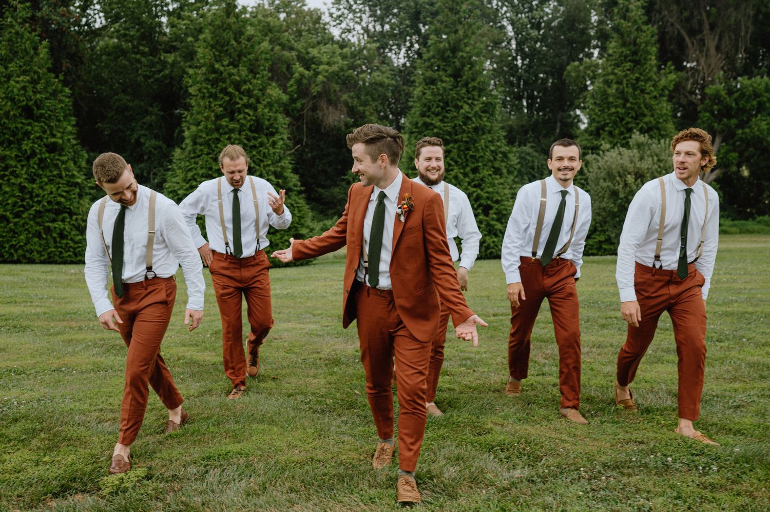 candid photograph of groomsmen in orange suits walking in backyard at wedding in maryland