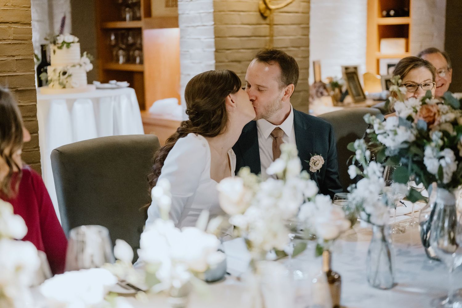 Wedding celebration at an intimate indoor venue with elegant floral centerpieces and table settings.