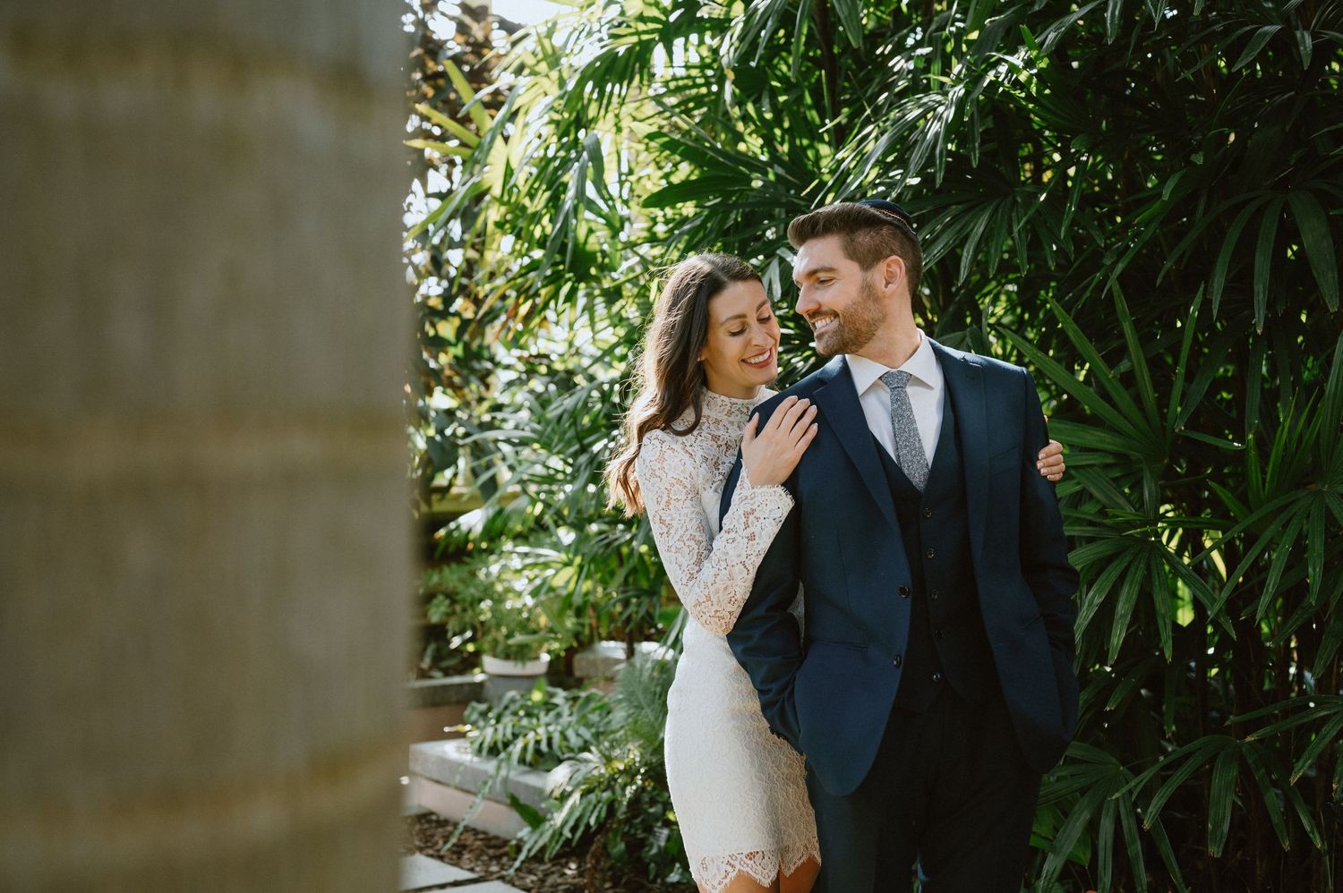 A tender moment shared between a couple among lush tropical greenhouse foliage.