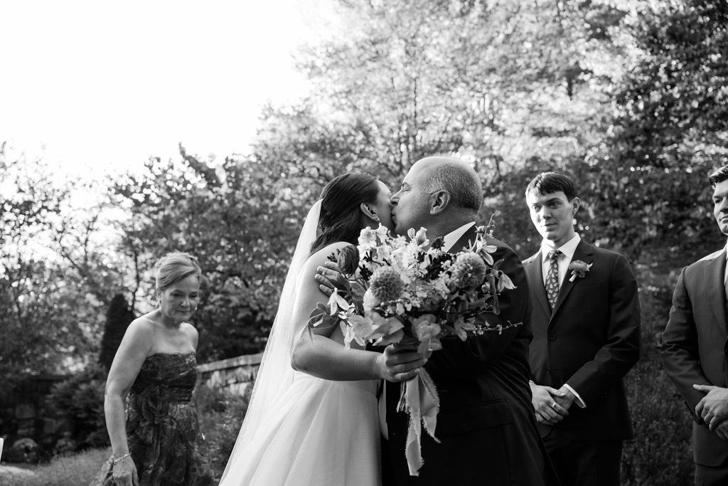 Wedding party walking along an outdoor path during a sunny ceremony.
