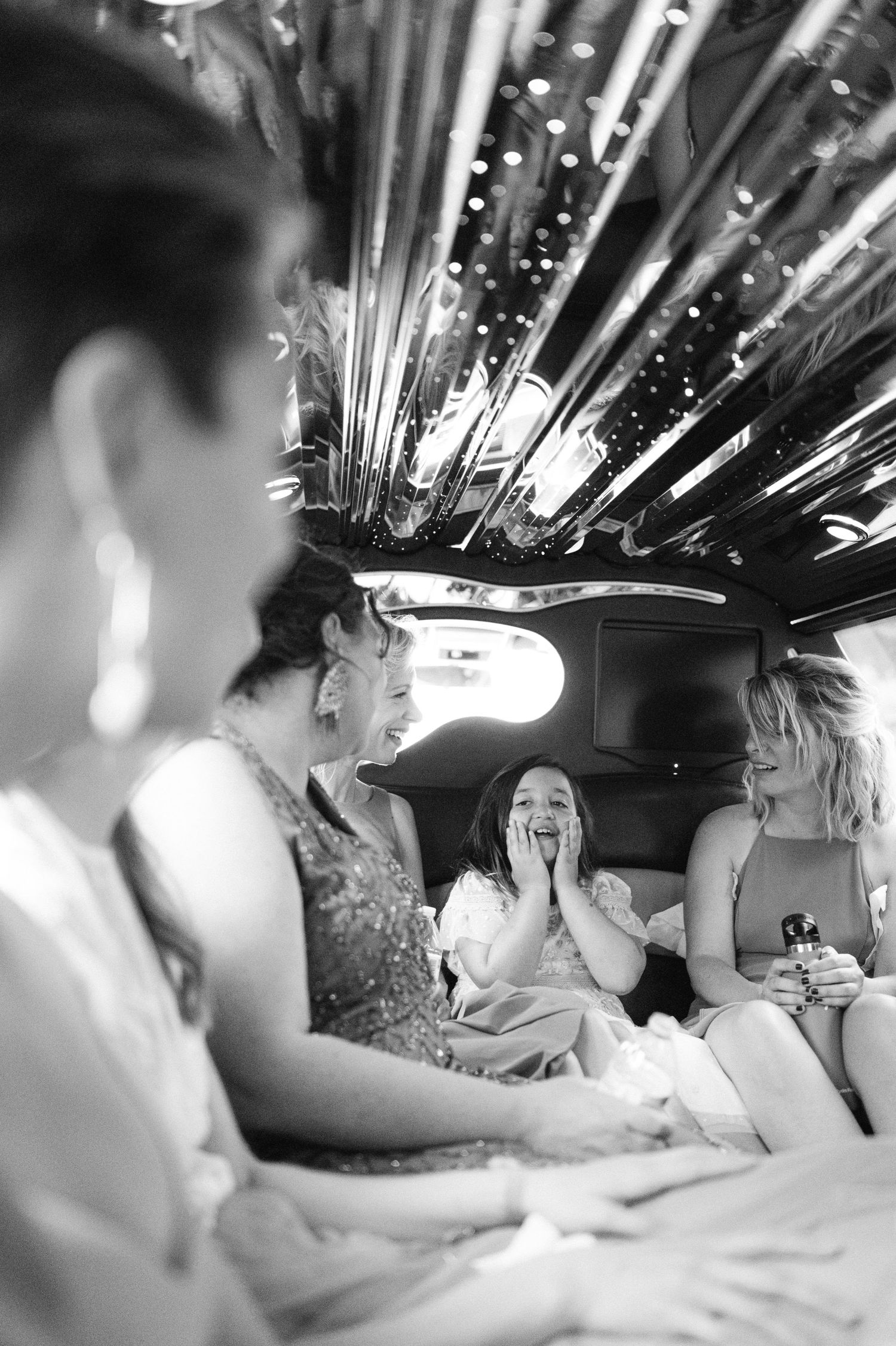 Wedding party celebrates in a limousine with sparkling lights overhead.