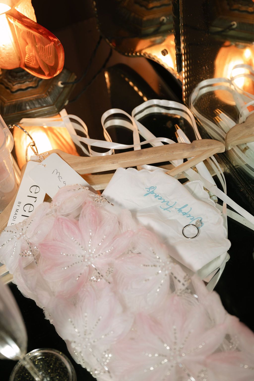 Pink tulle ballet tutus with sparkly sequins hang on white hangers in a dimly lit backstage area.