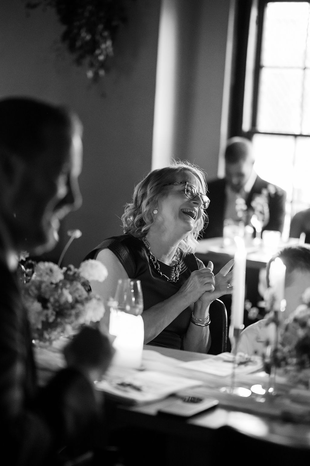 Black and white candid shot of wedding guests dining at a reception table Fadensonnon in Baltimore