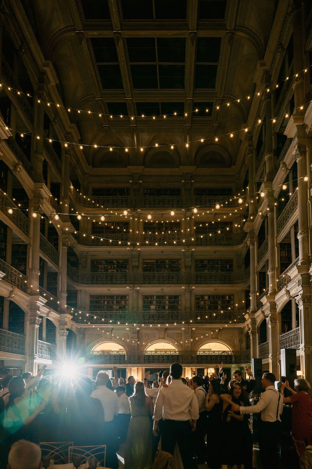 Wedding reception venue decorated with string lights and columns creating a warm, festive atmosphere at George Peabody Library Wedding