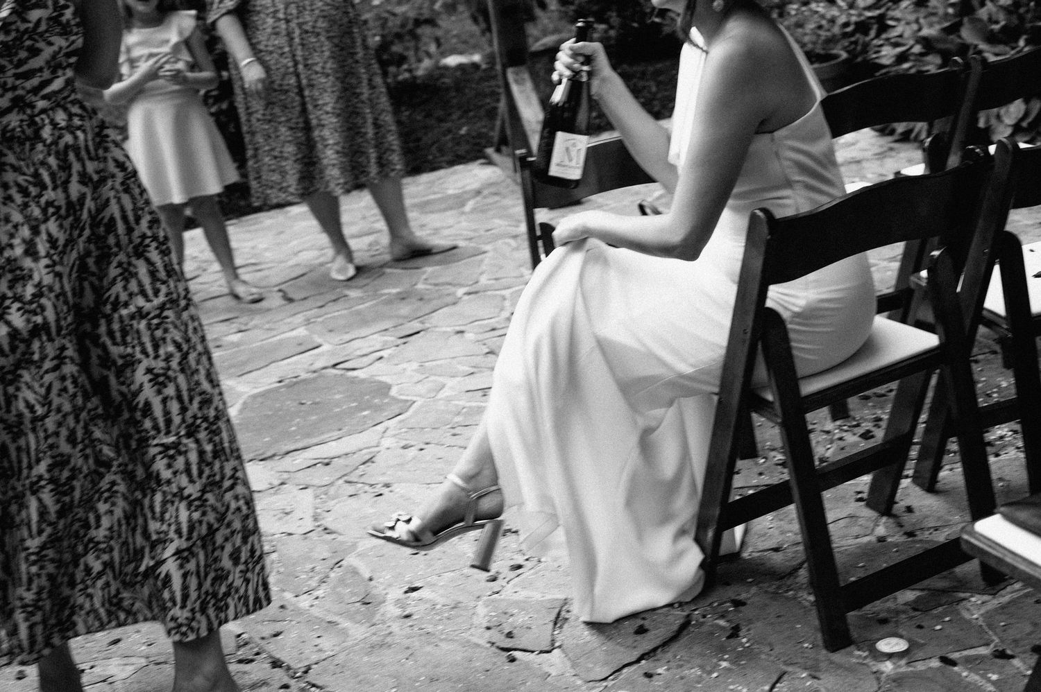 Black and white wedding photo sequence showing people sitting on wooden benches in an outdoor setting.