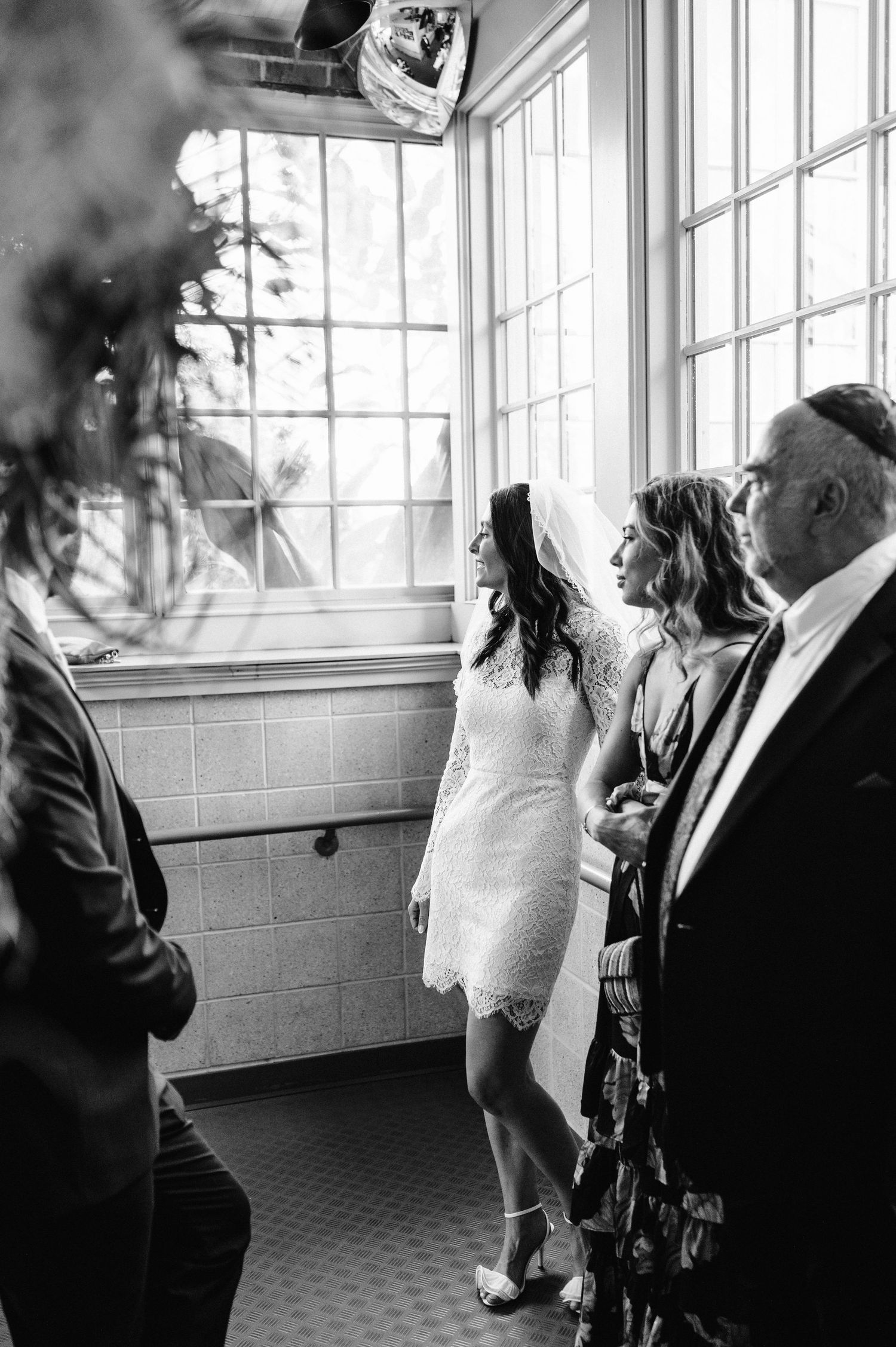A wedding celebration scene in a sunlit room with large windows.
