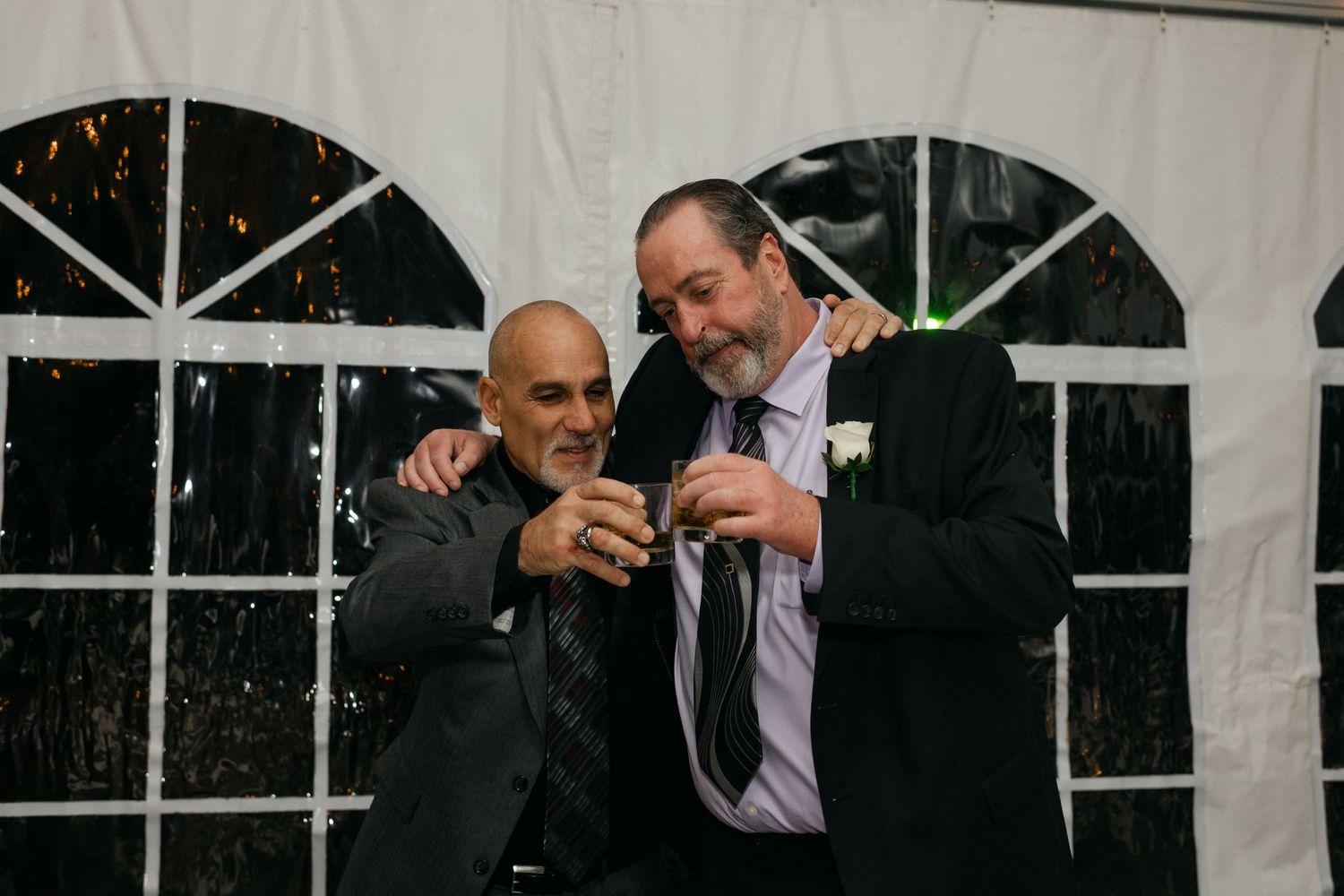 Two guests enjoying drinks and conversation during an evening wedding reception.