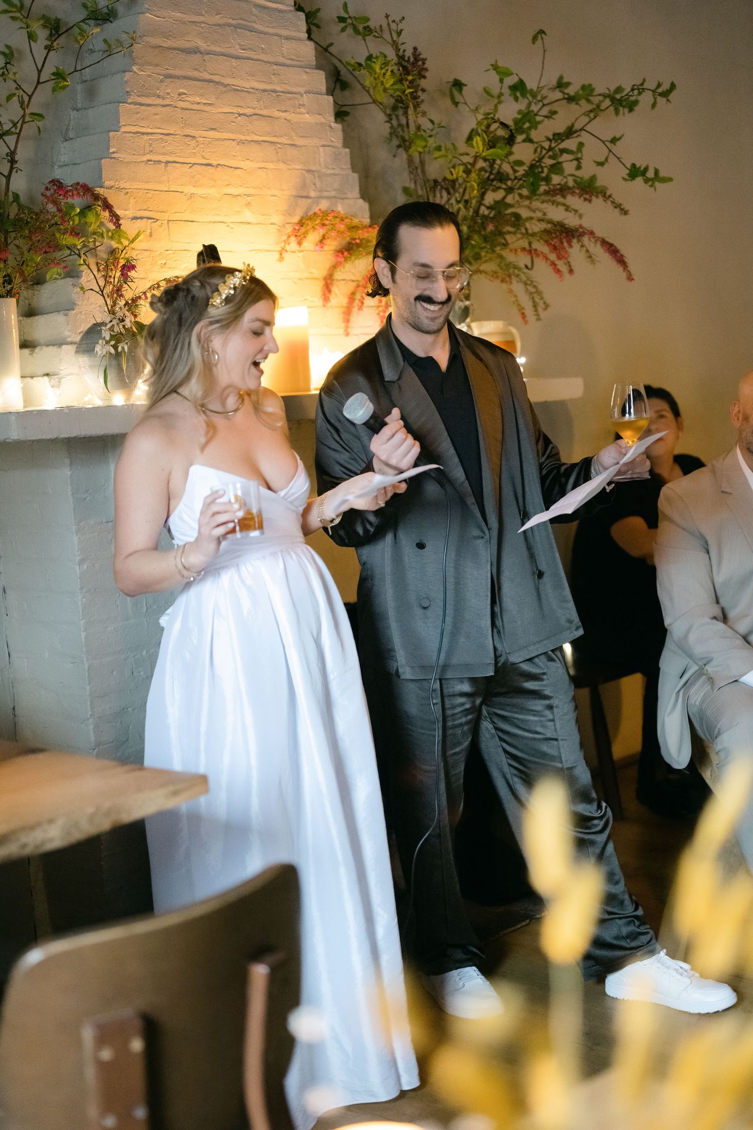 A couple shares a joyful moment during a wedding celebration in an intimate indoor setting with white decor and greenery at Fadensonnen