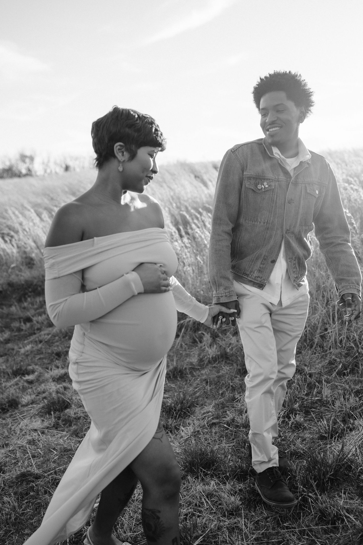 pregnant couple walks together in field in maryland
