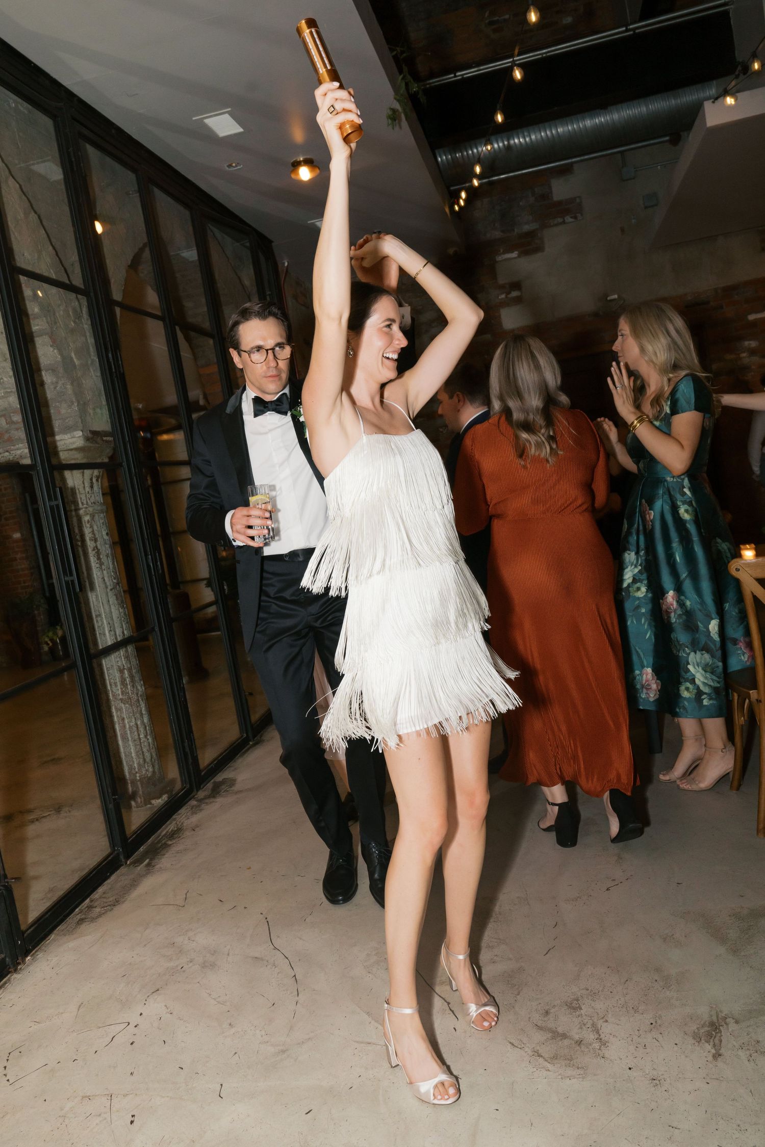 Celebratory dancing at a wedding reception with guests in formal attire.