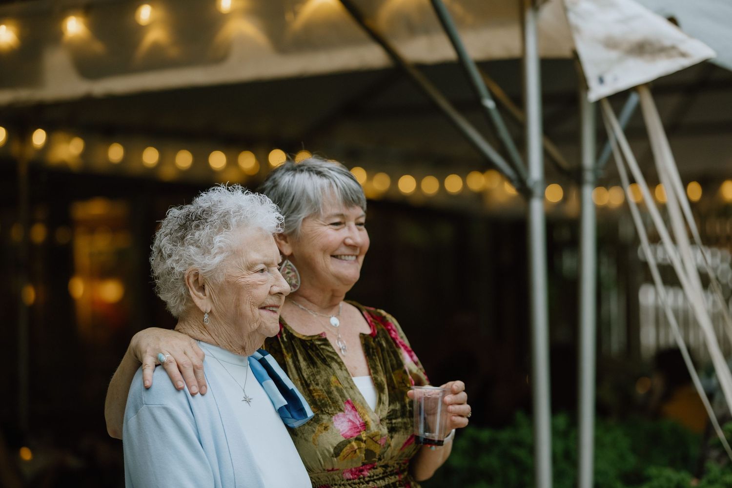 Two people enjoying drinks and conversation under evening string lights.