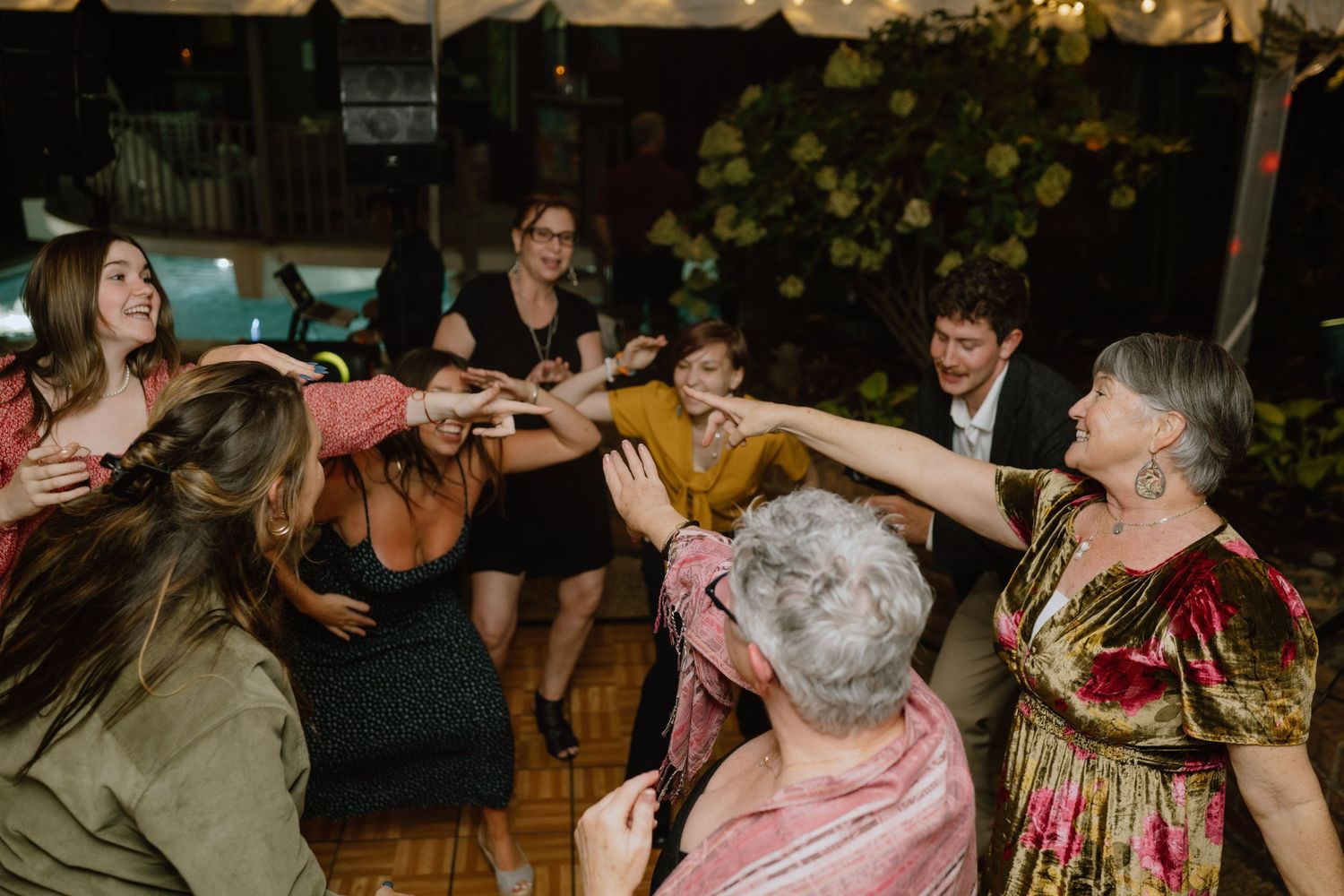 Group of party guests dancing and celebrating together under a tent.