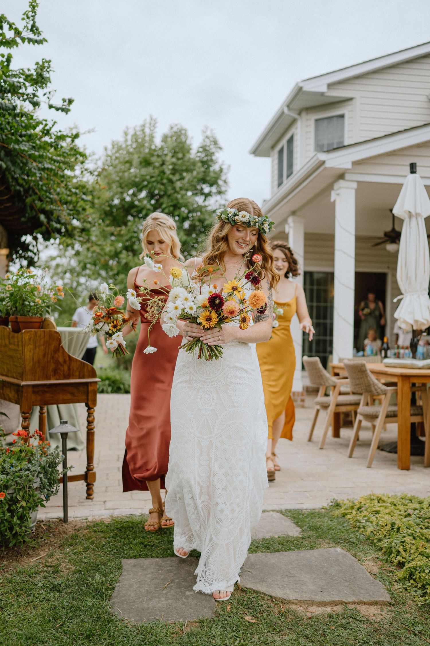 bride in lace wedding dress walking with bridesmaids boho vibes backyard wedding with fireworks in maryland