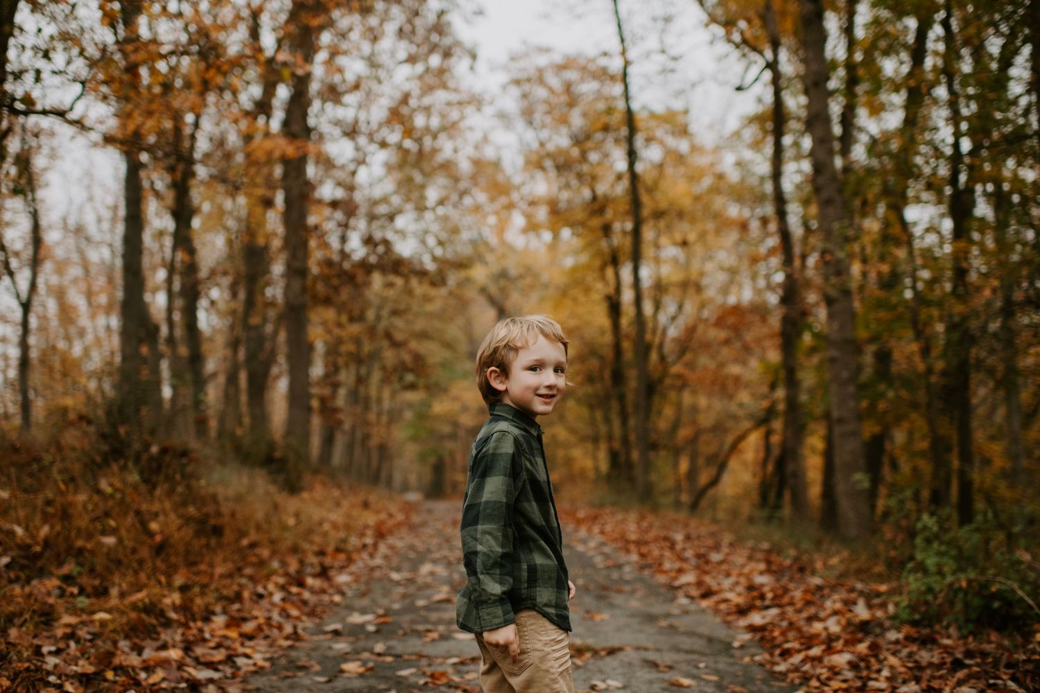 Candid autumn portrait on a forest trail with fallen leaves.