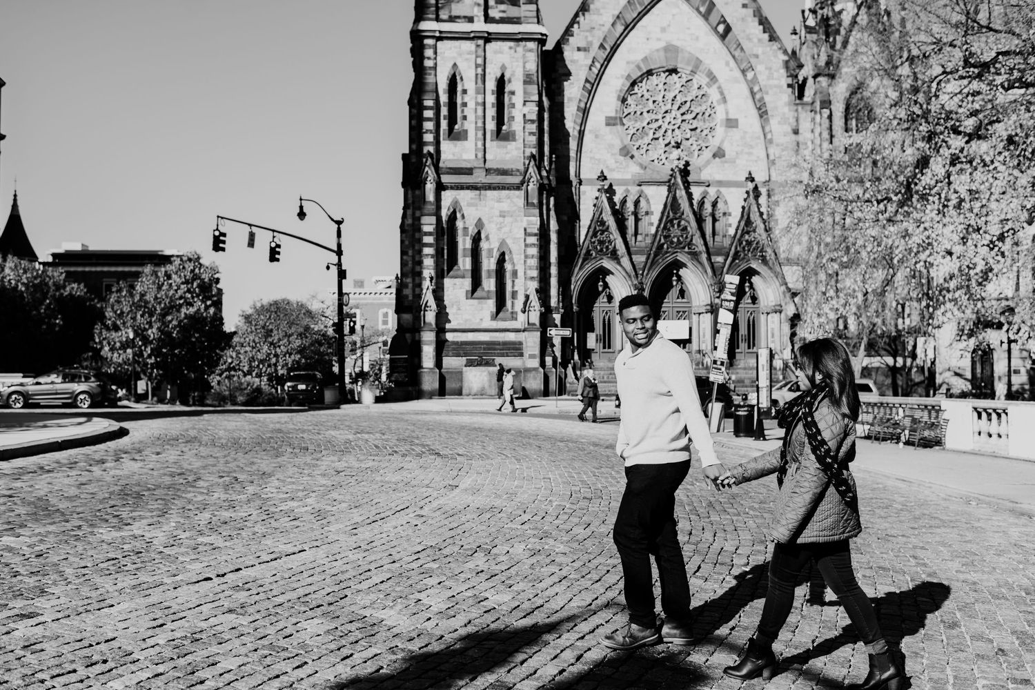 A black and white photo of a couple walking near a historic church.