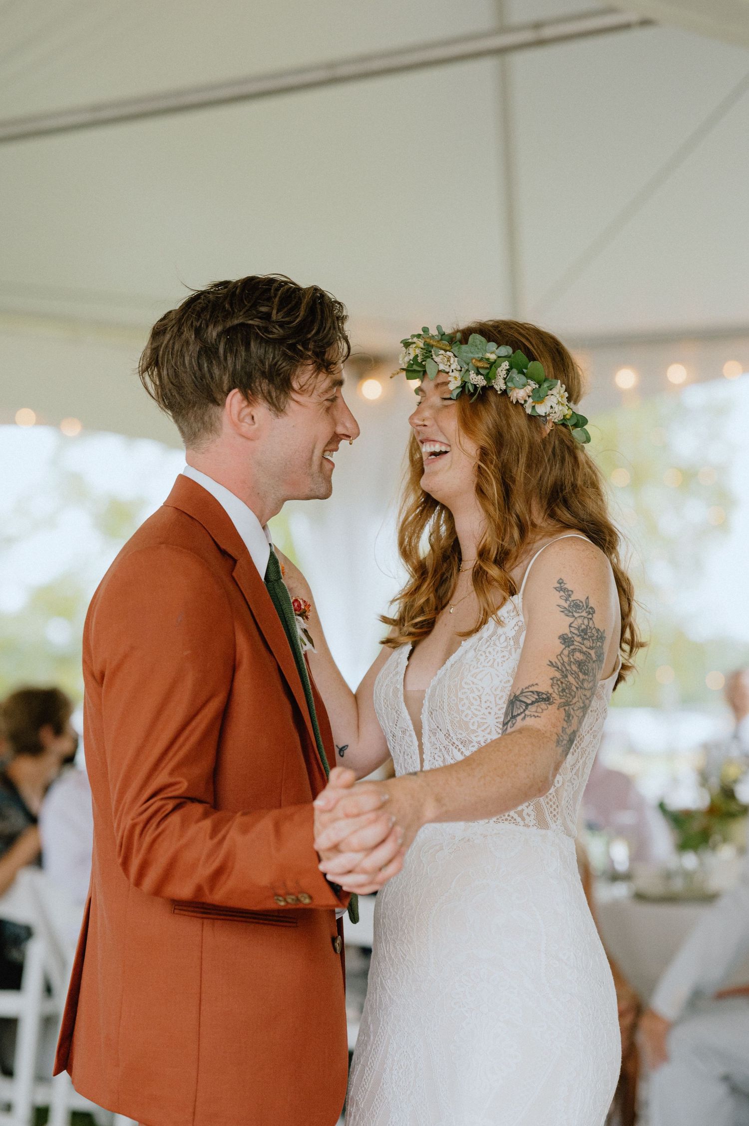 A joyful dance moment captured under a white tent with string lights overhead.