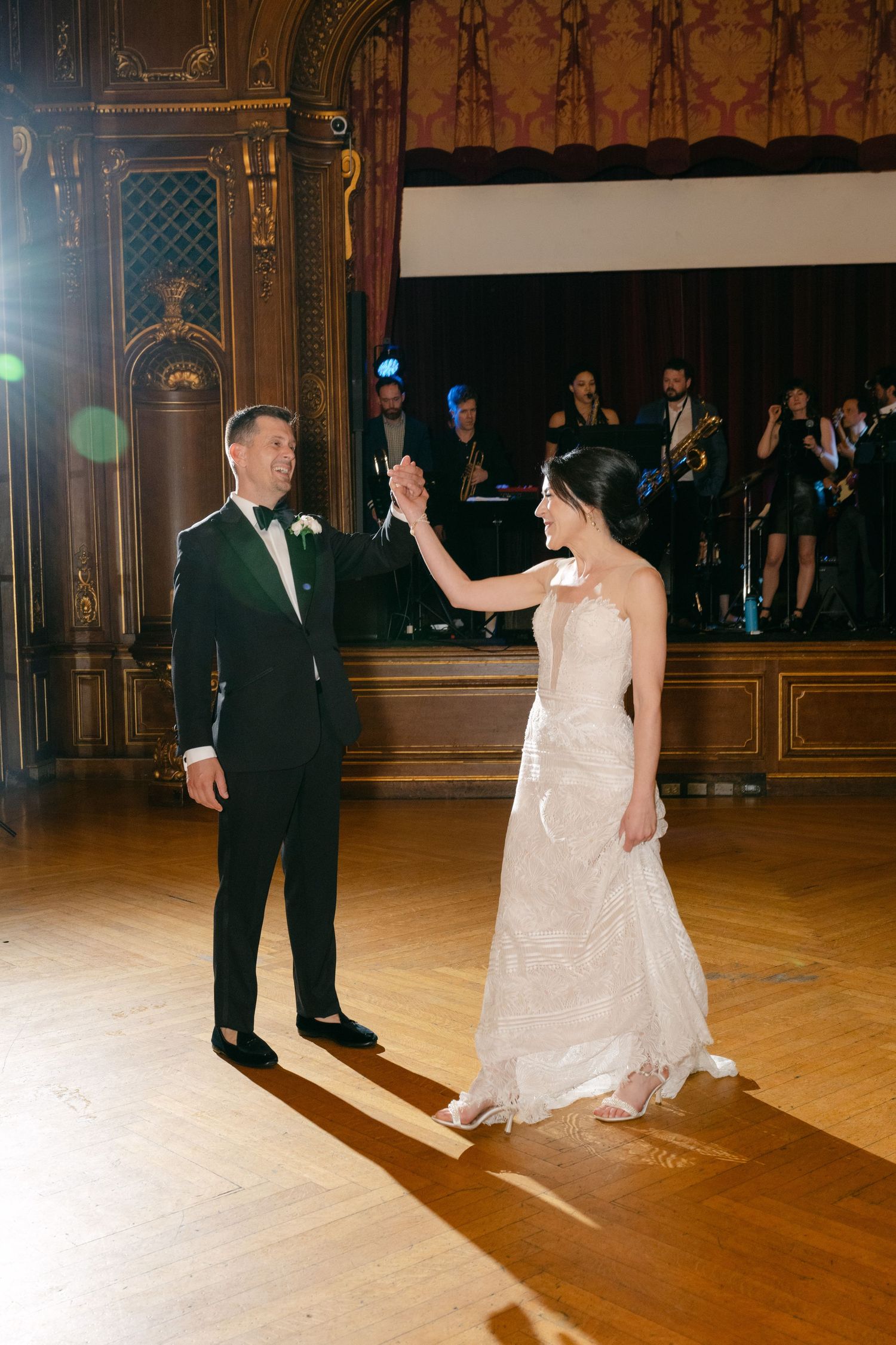 A couple sharing their first dance on a grand wooden ballroom floor.