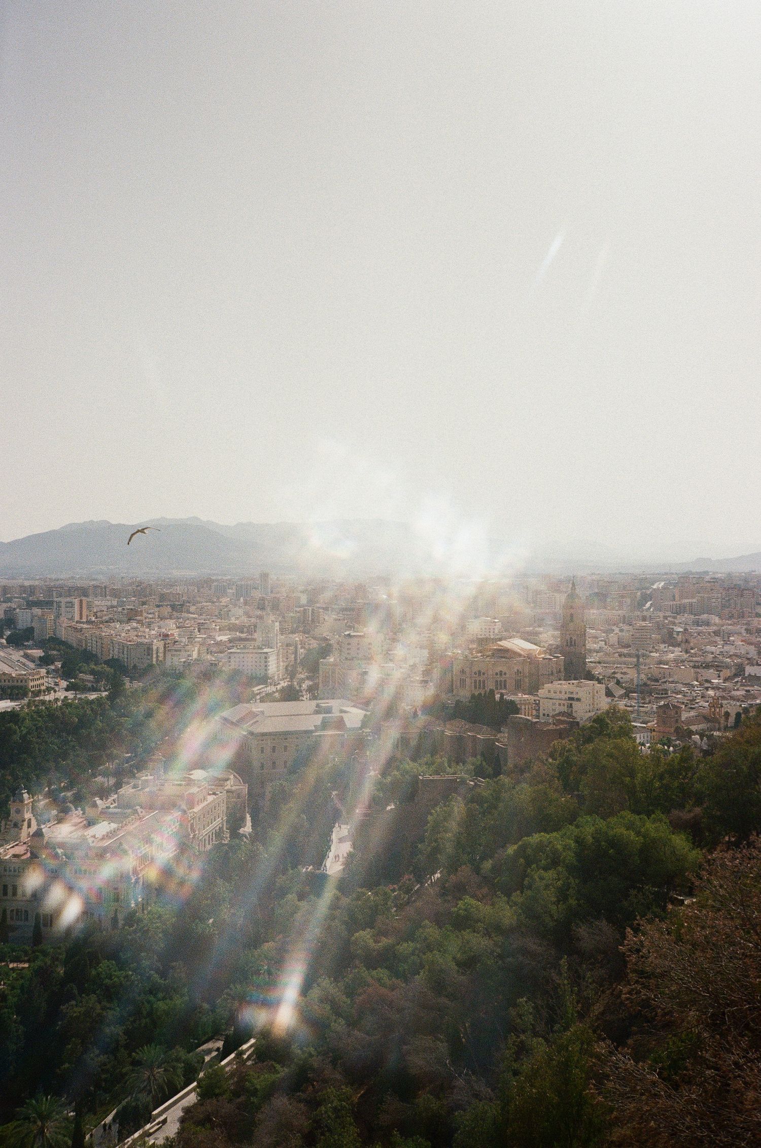 Sunlit cityscape with dramatic lens flare overlooking a Mediterranean urban landscape.