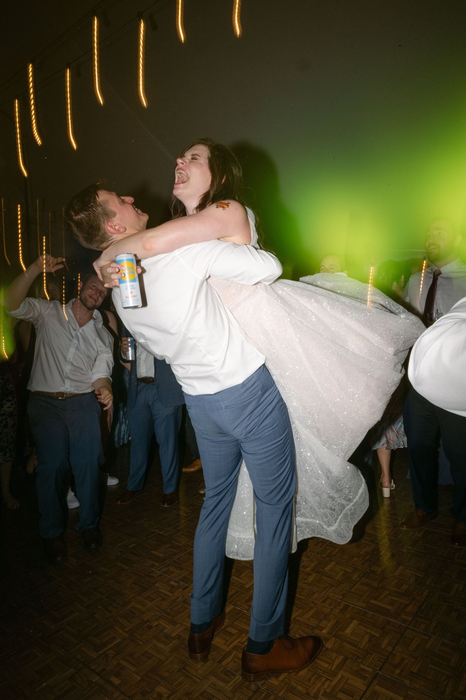 A couple dances and dips dramatically on a dark dance floor with string lights overhead.