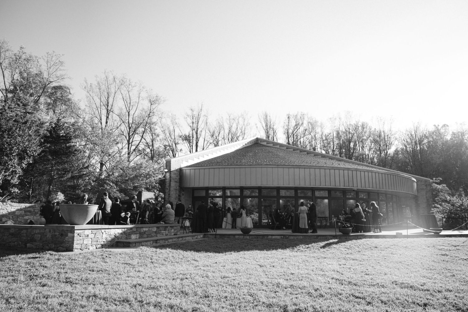 Black and white photo of a rustic wedding venue building with guests gathered outside.