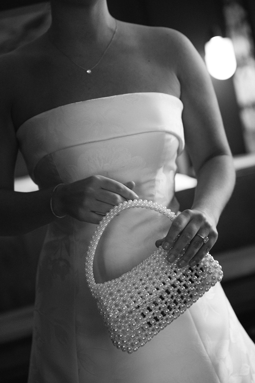 Close-up of beaded bridal clutch against white wedding dress.