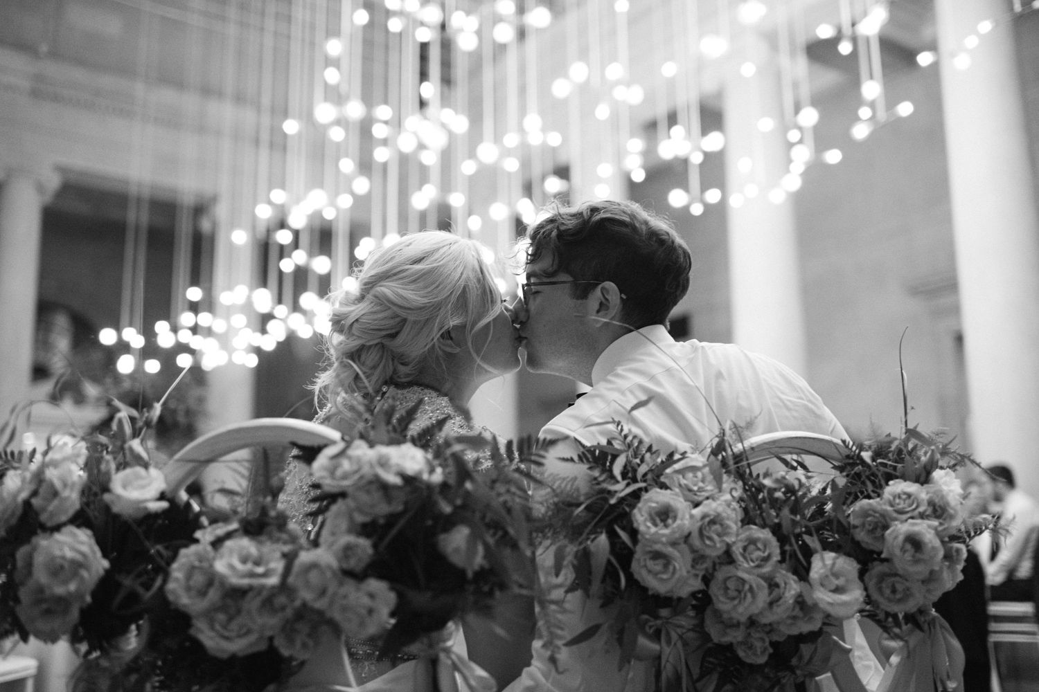 Wedding reception decor featuring elegant floral arrangements under sparkling overhead lights.