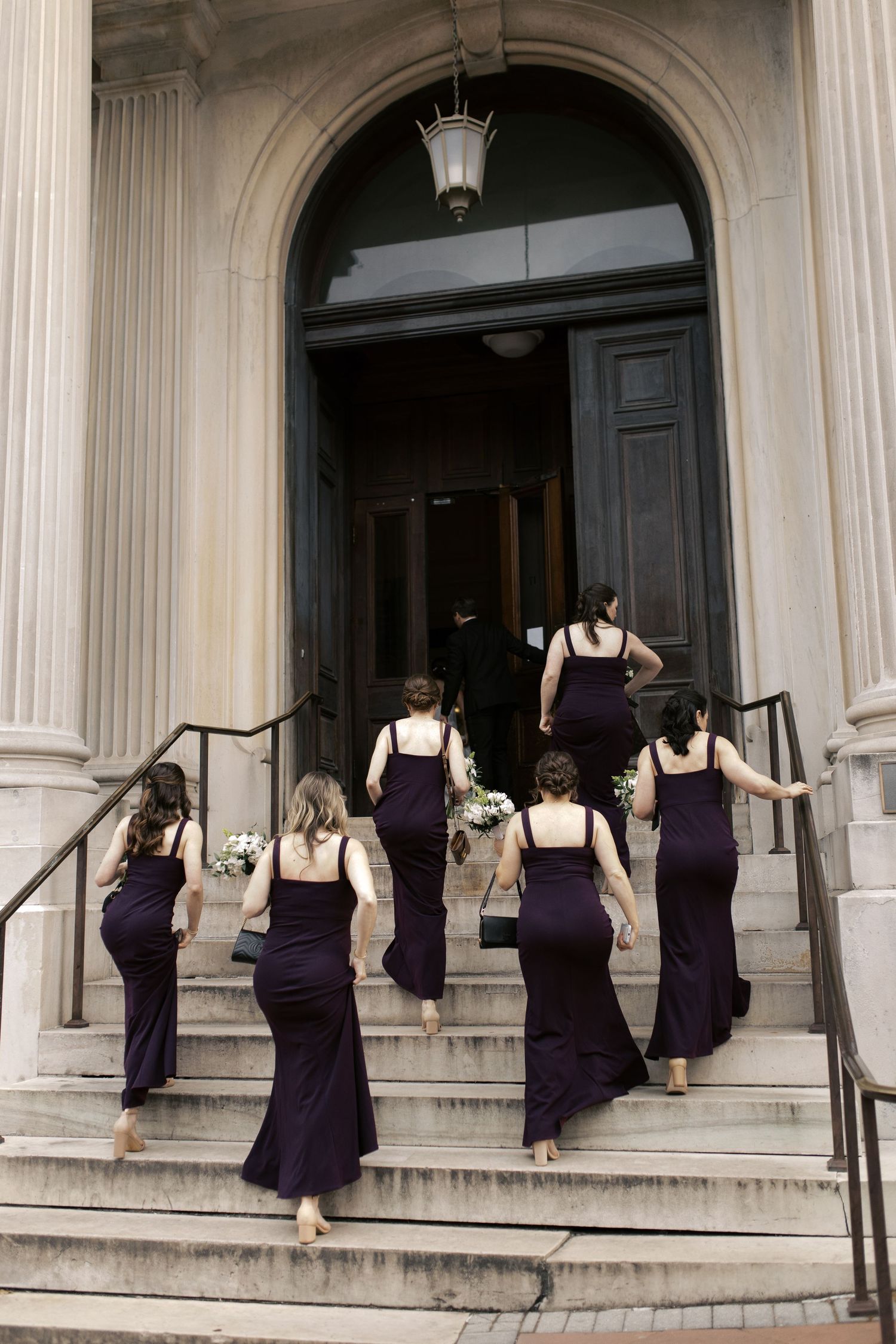 Group walking up grand stone steps of historic building entrance.