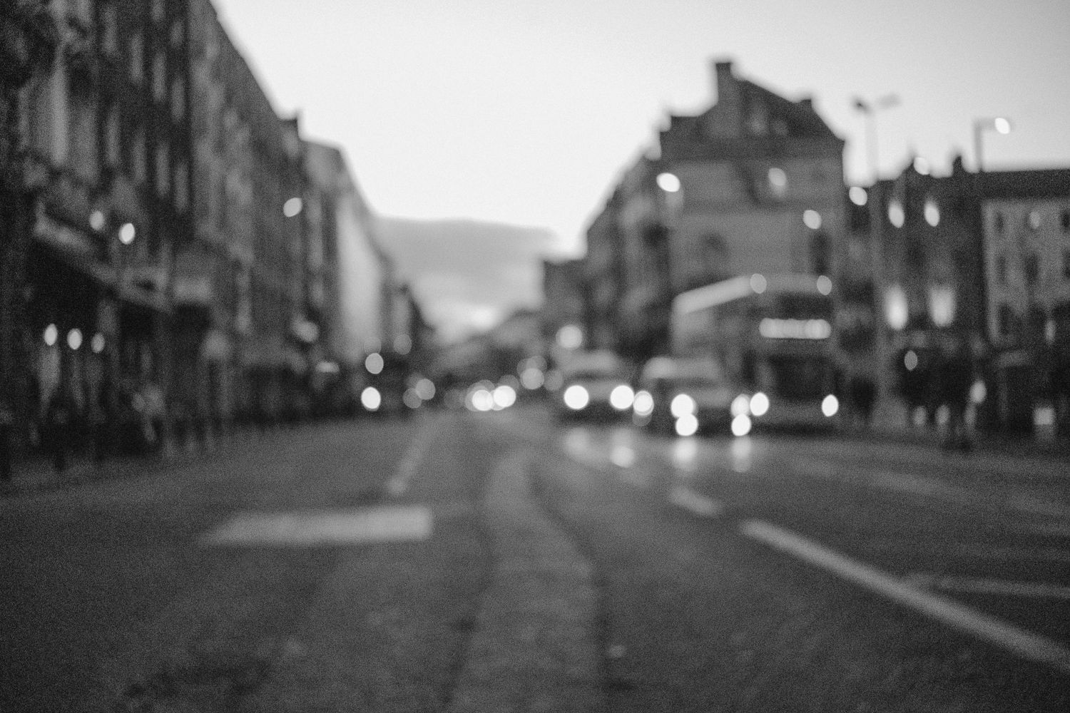 Blurred city street at dusk with bokeh lights creating a dreamy urban atmosphere.