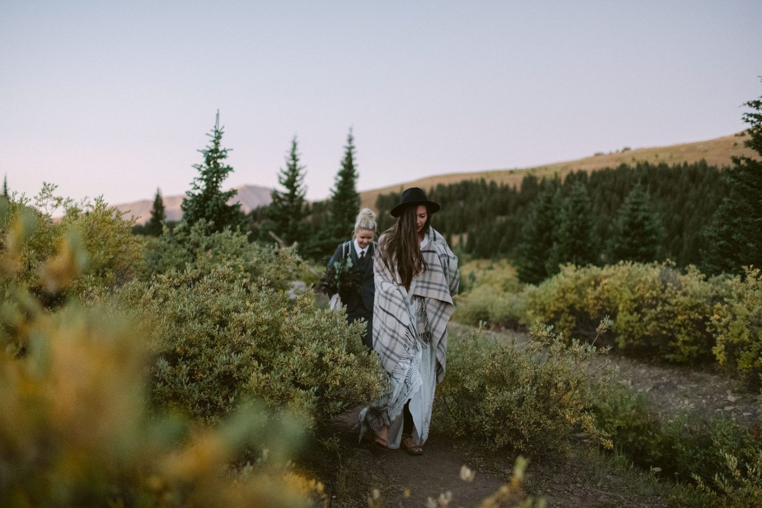 Couple walking through mountain wildflowers at dusk.