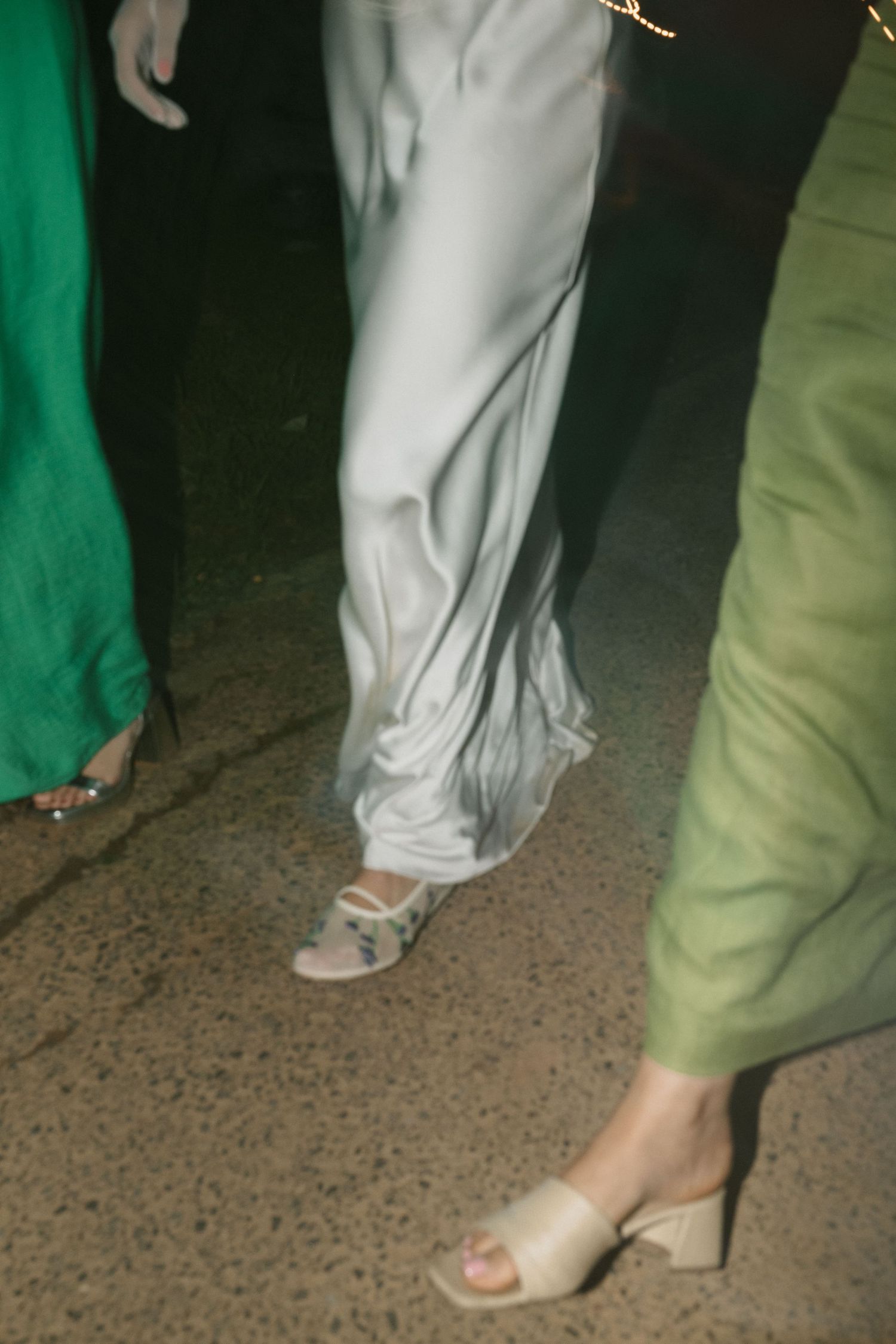 Wedding guests in formal attire showing stylish footwear on a dance floor.